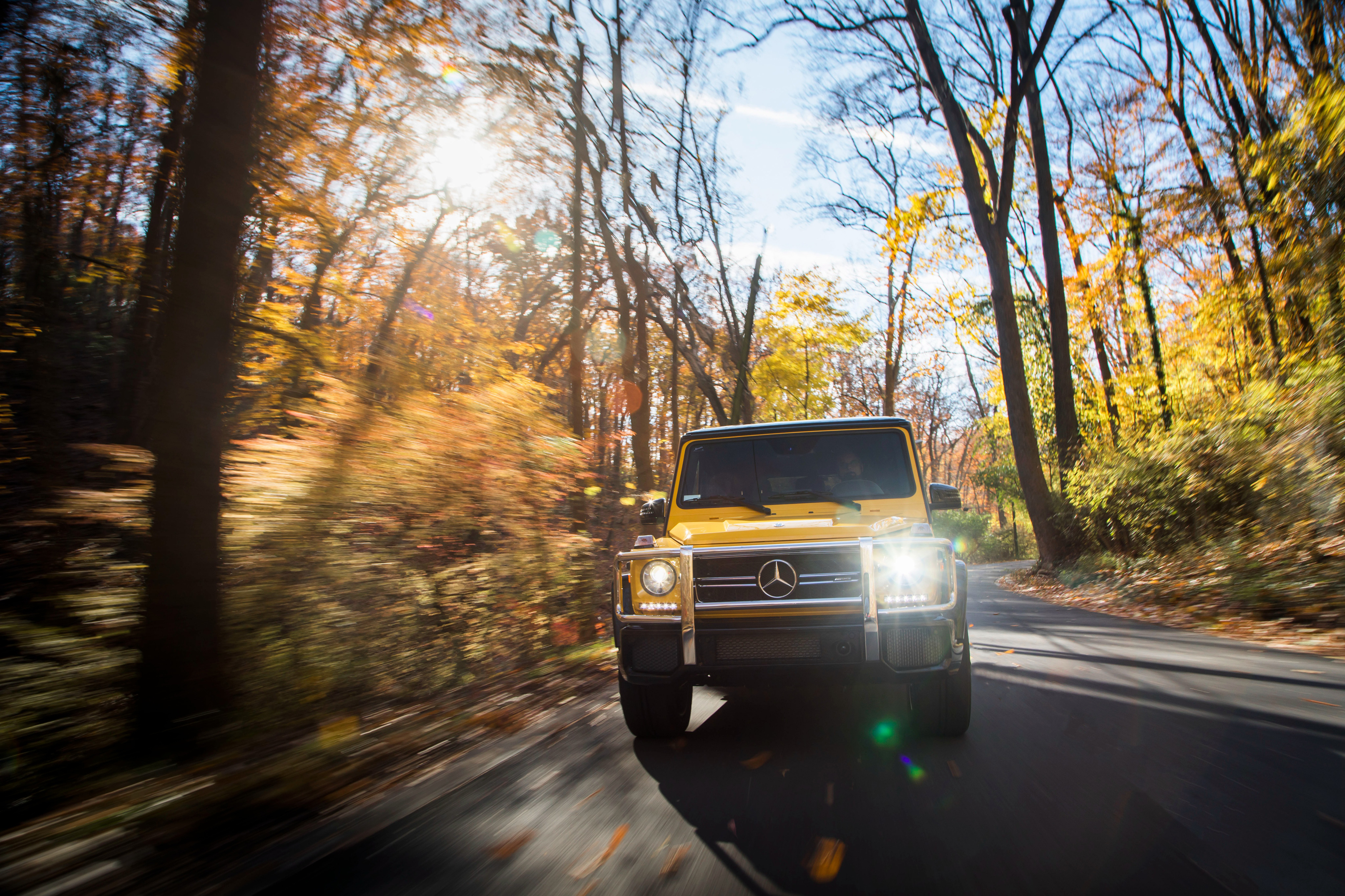 Yellow Mercedes G-Class driving on a road in autumn HD Wallpaper