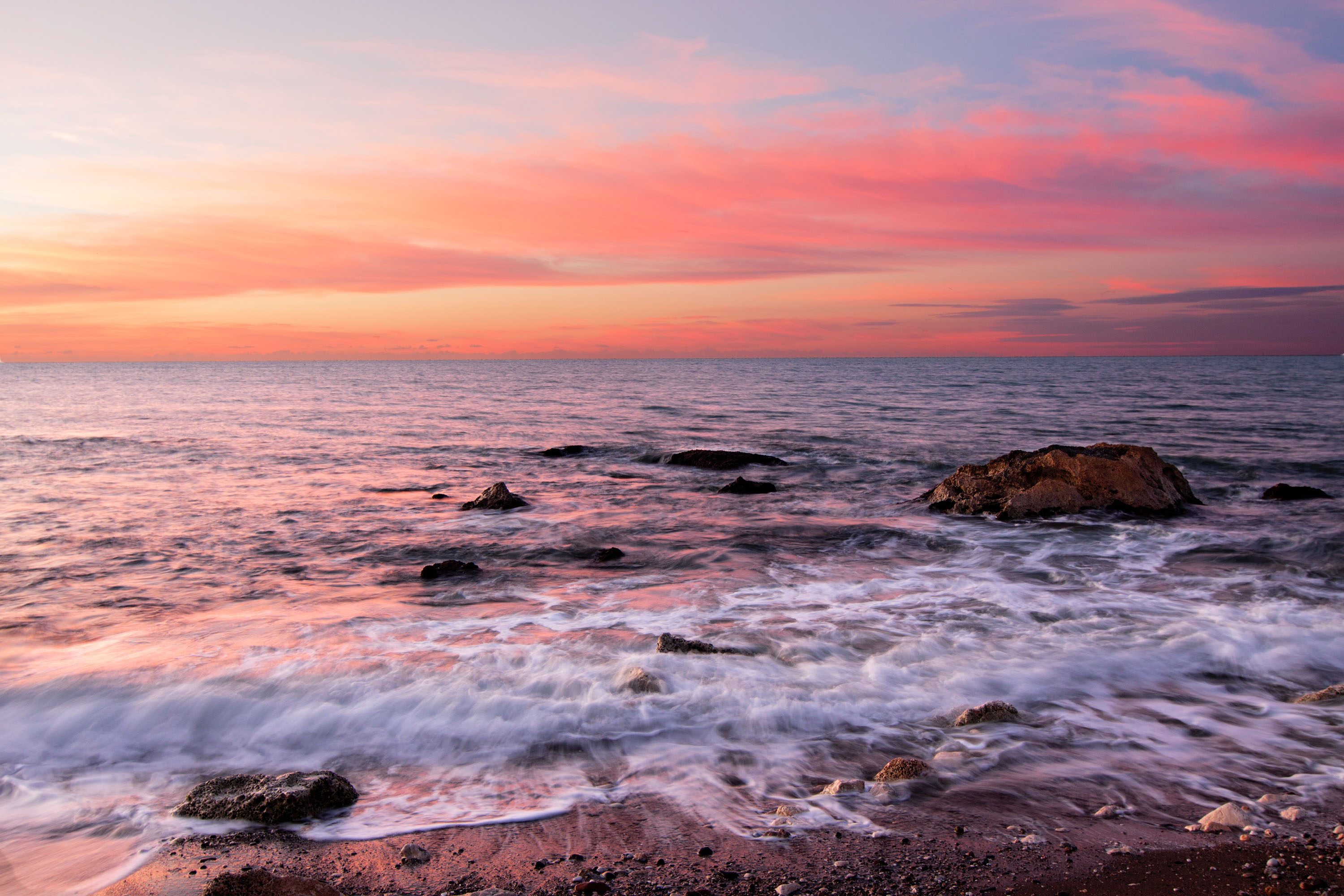 Sunset over the ocean with pink clouds and rocks HD Wallpaper