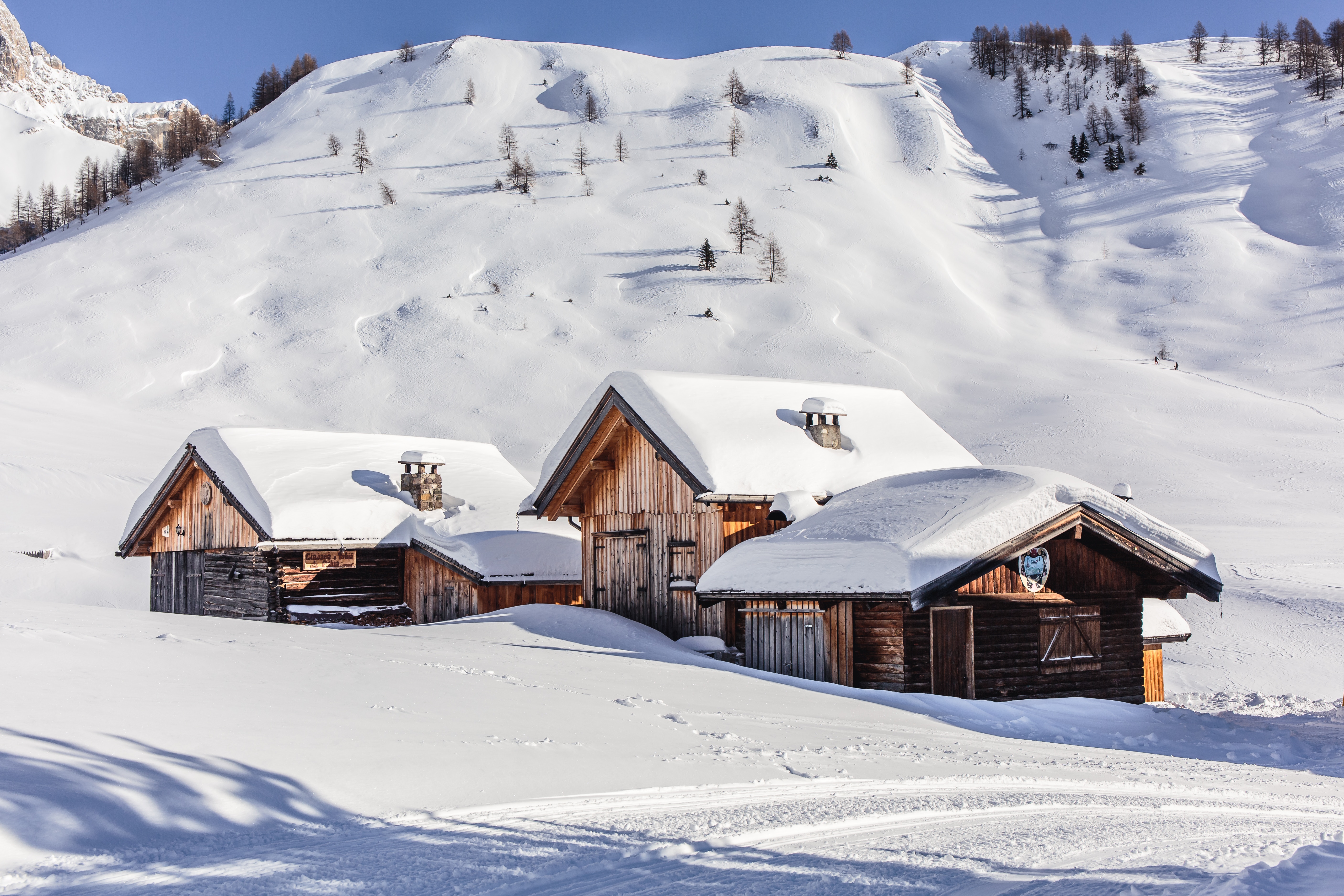 Wooden chalets covered in snow on a mountain slope HD Wallpaper