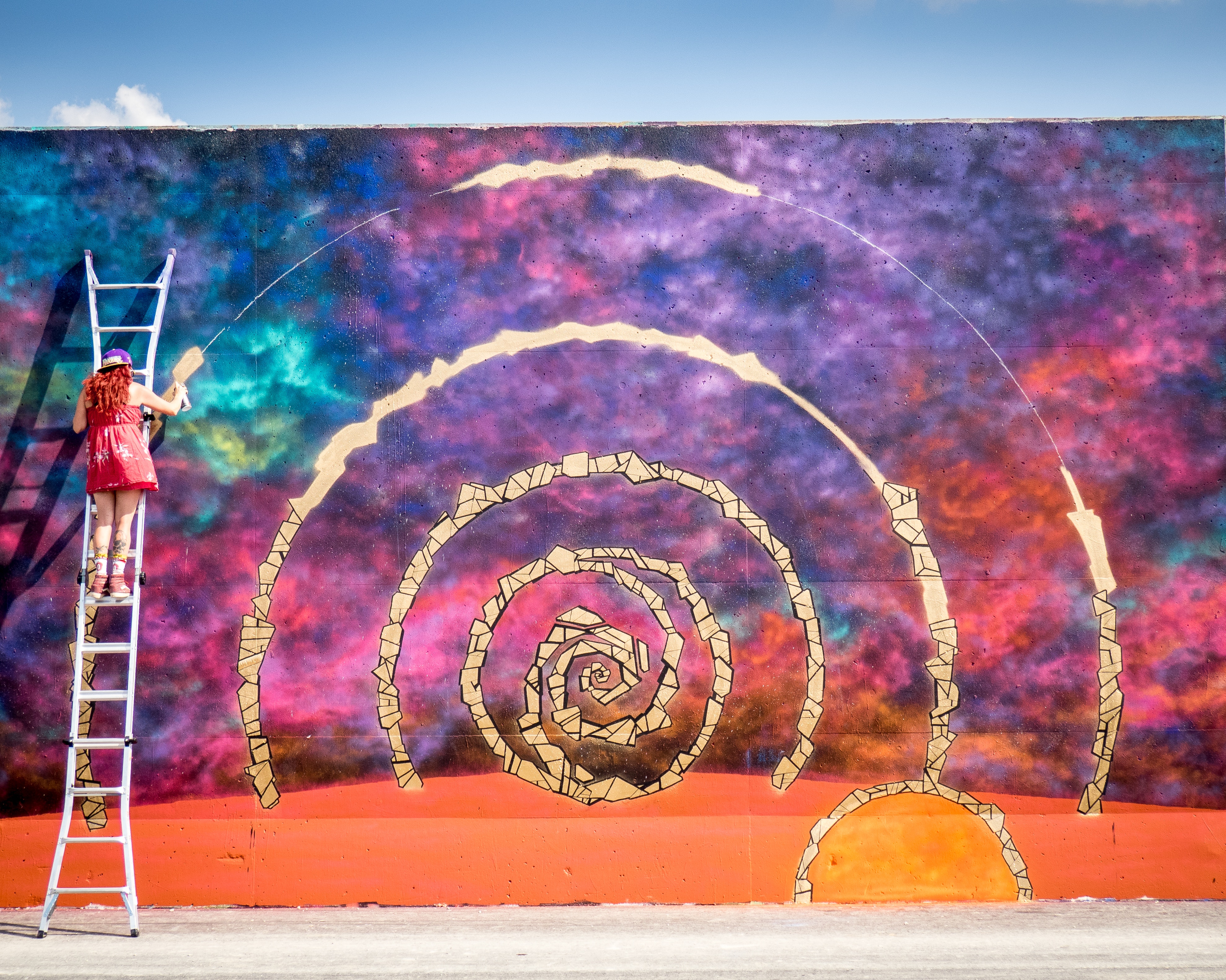 Artist painting a colorful spiral mural on a wall HD Wallpaper