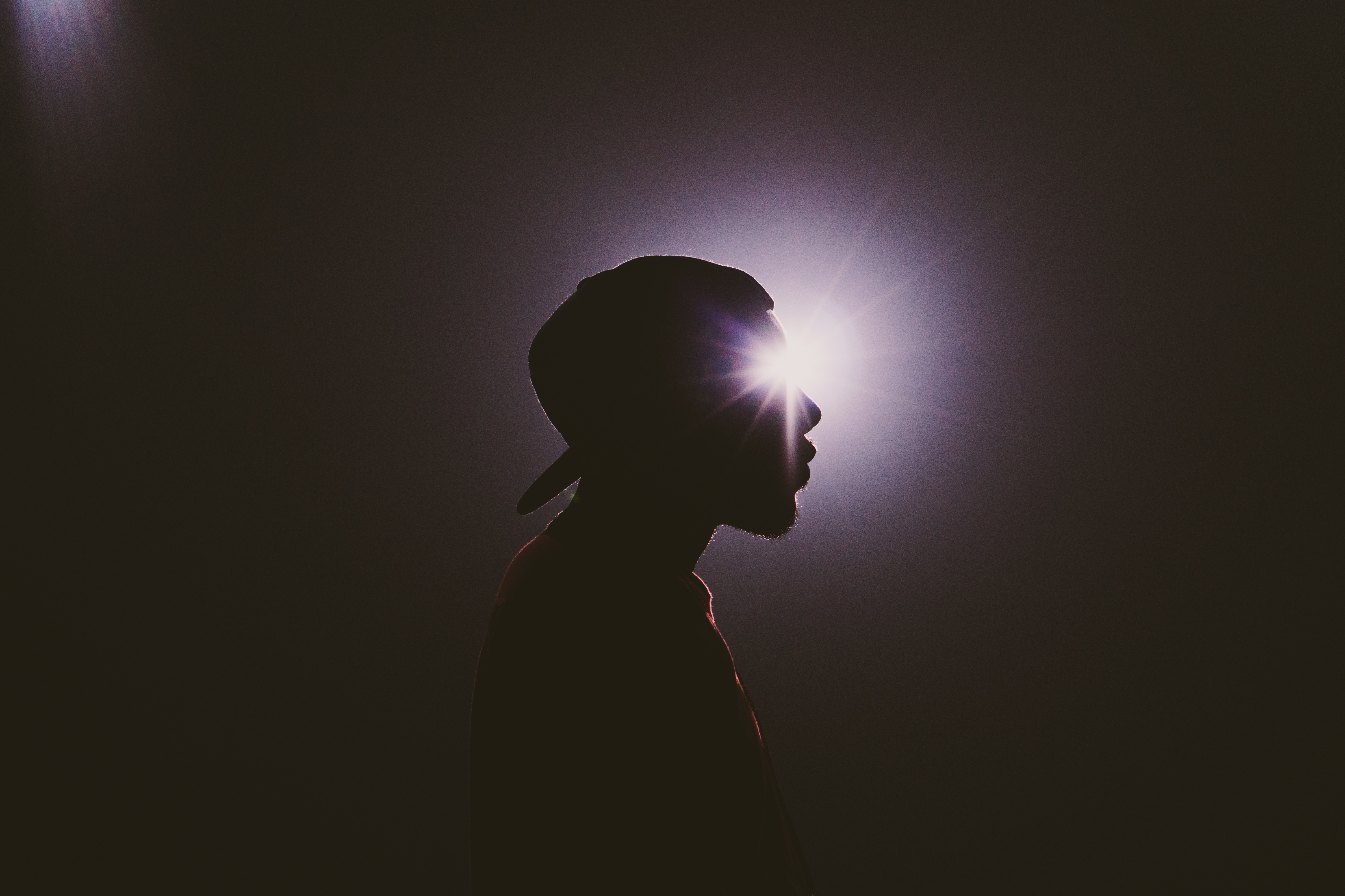 Silhouette of a man wearing a cap with lens flare HD Wallpaper