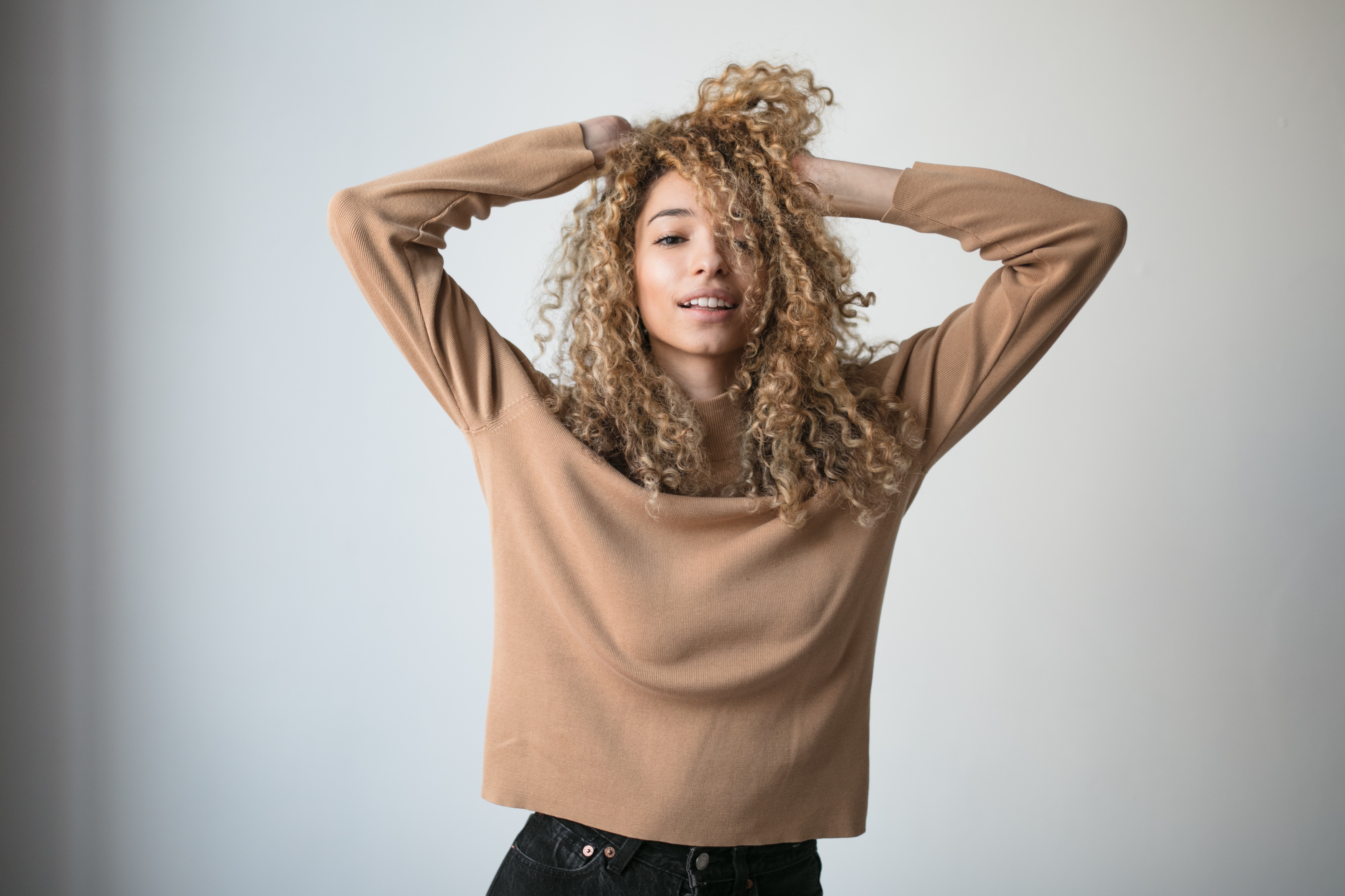 Woman with curly hair touching her head HD Wallpaper
