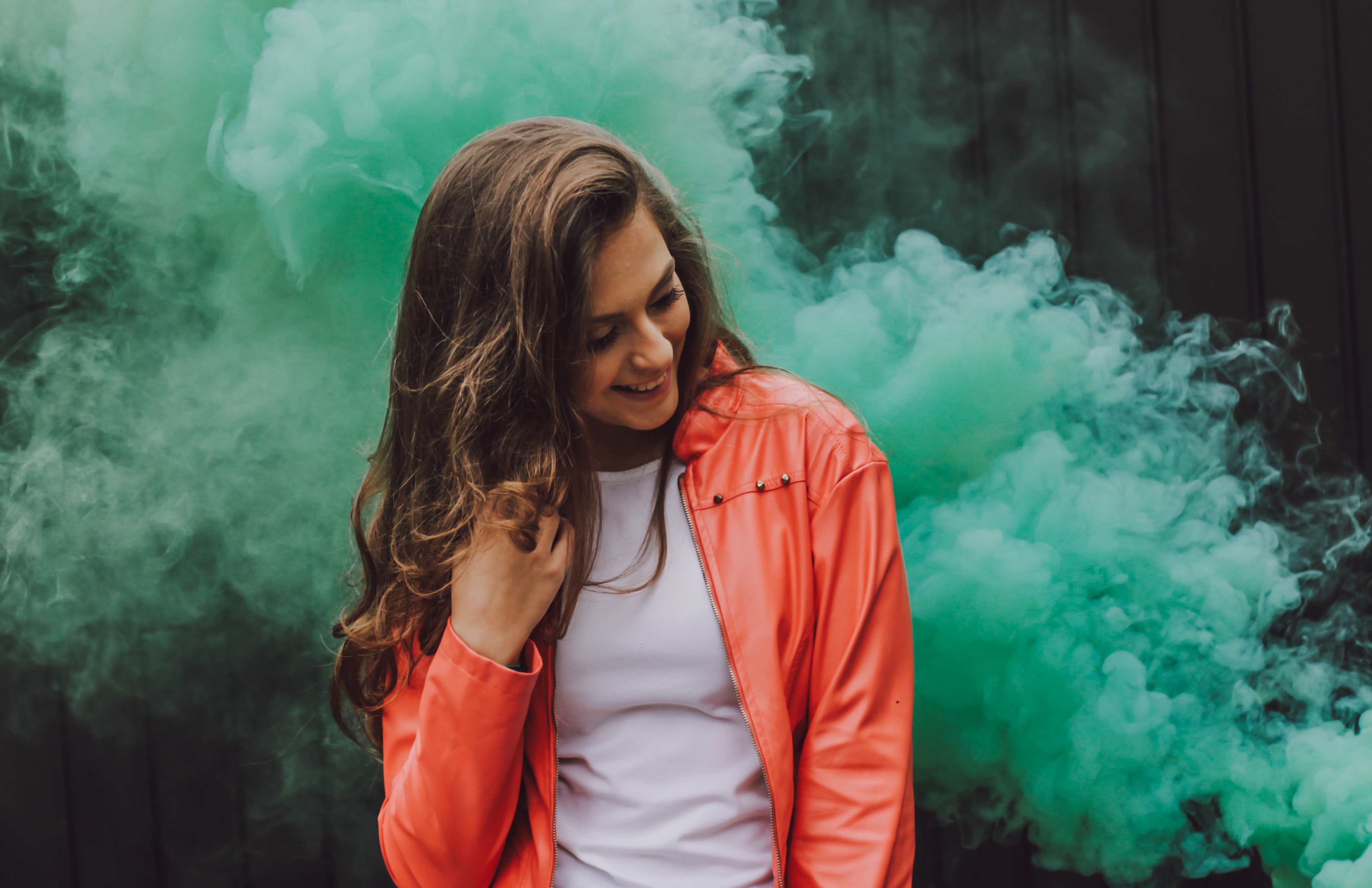 Woman in orange jacket with green smoke HD Wallpaper