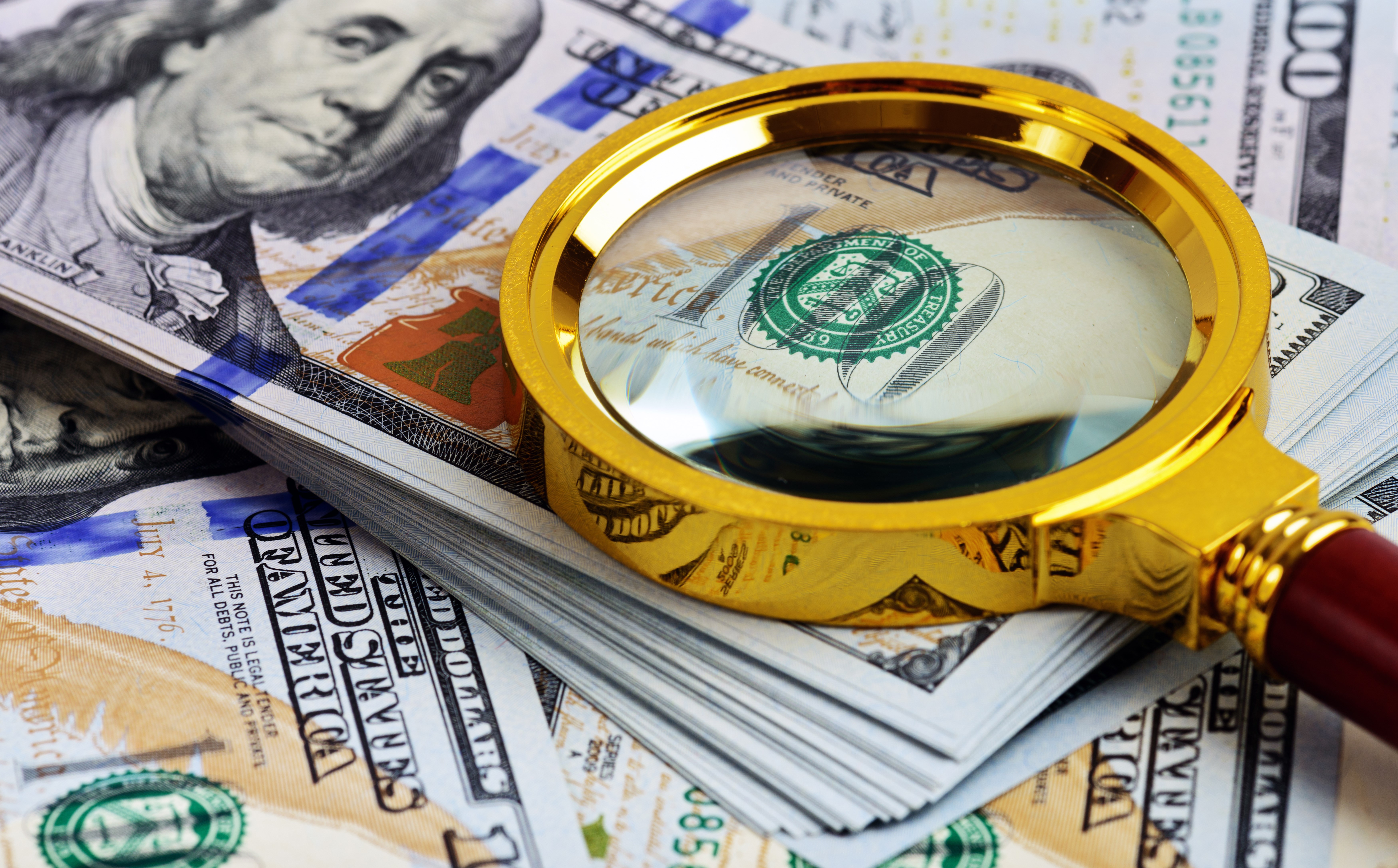 Magnifying glass over US dollar bills HD Wallpaper