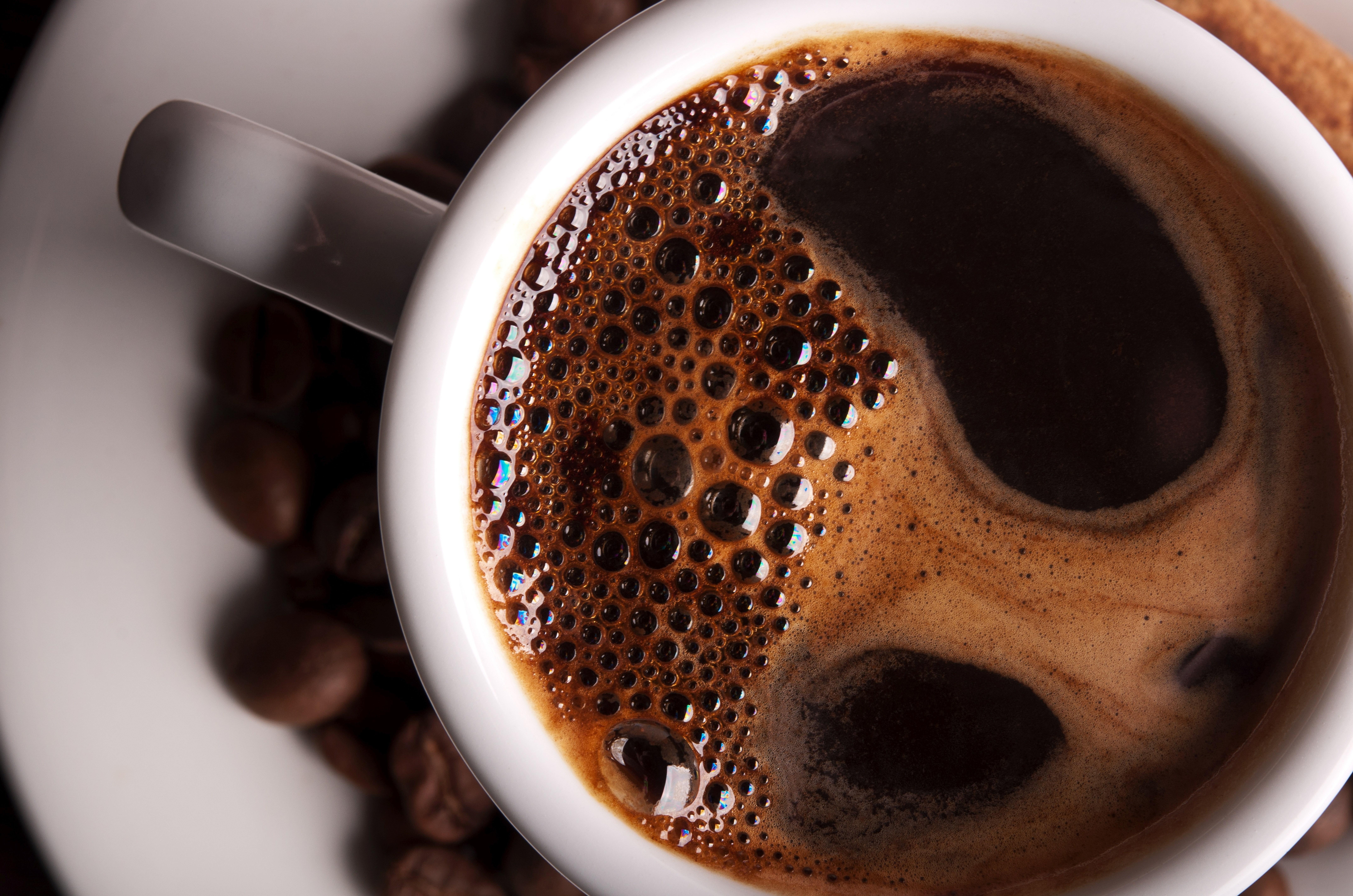 Close-up of coffee in a white mug with coffee beans HD Wallpaper