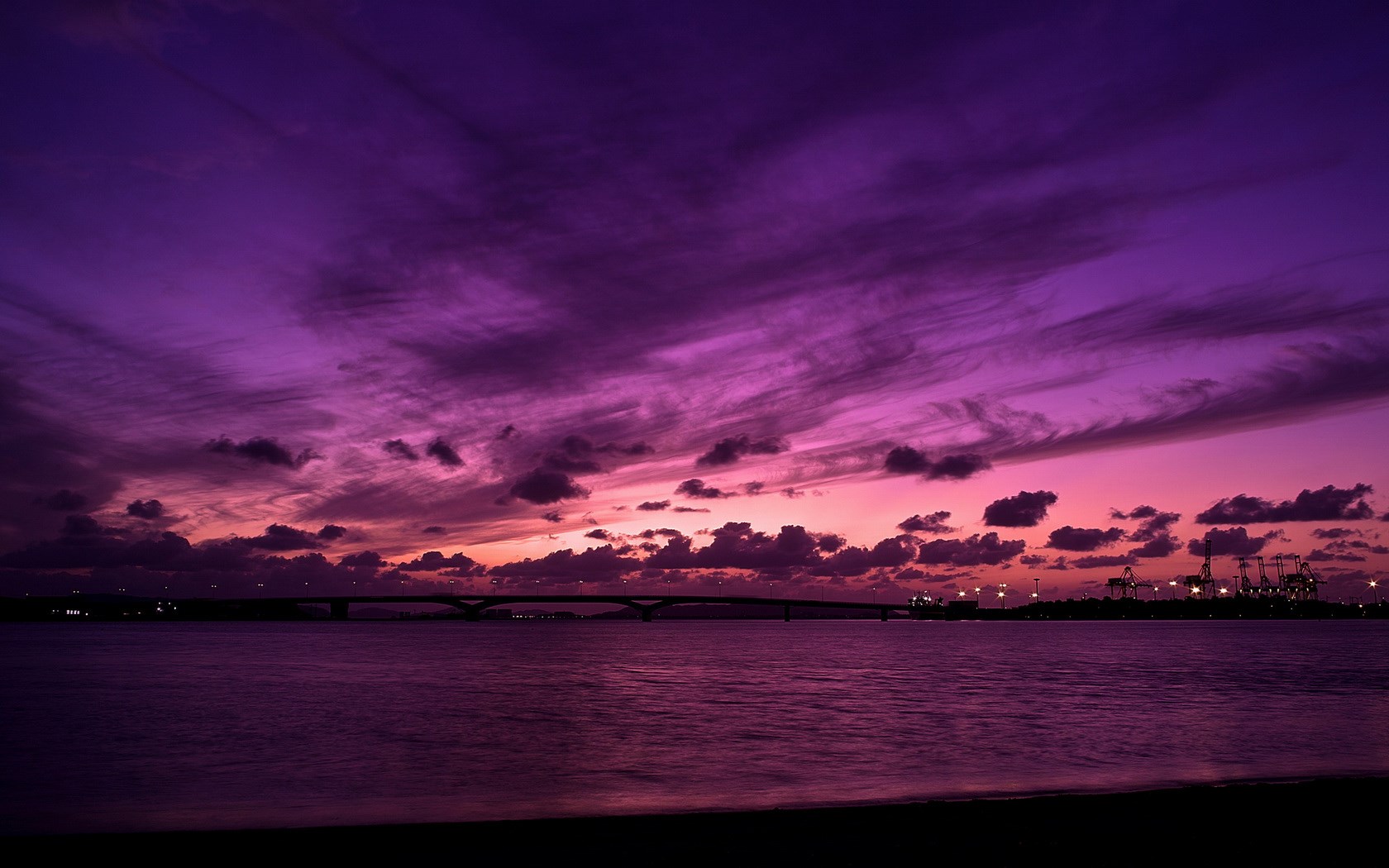 Purple sunset over water with bridge and cranes HD Wallpaper