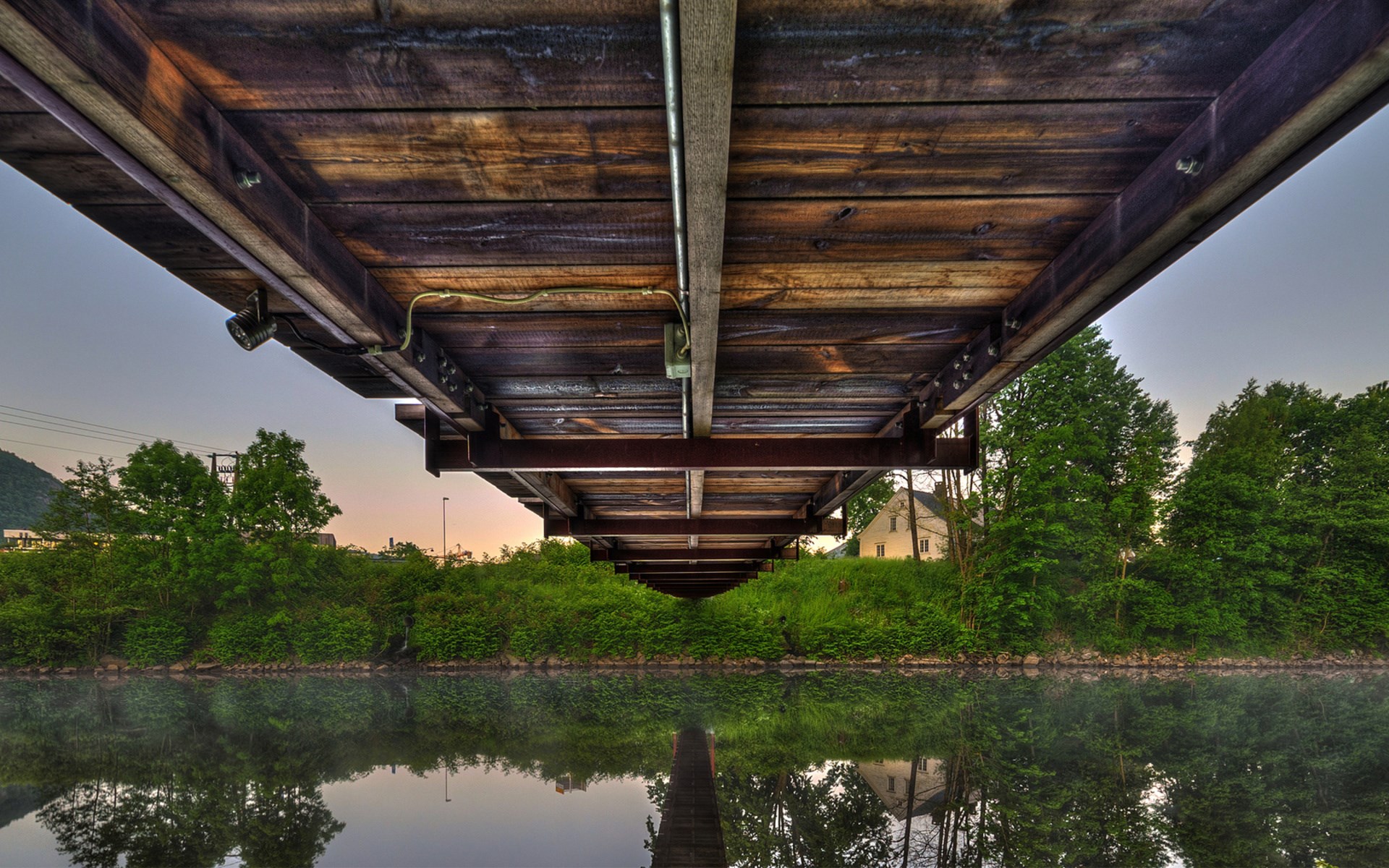 Underneath a wooden bridge reflected in water HD Wallpaper