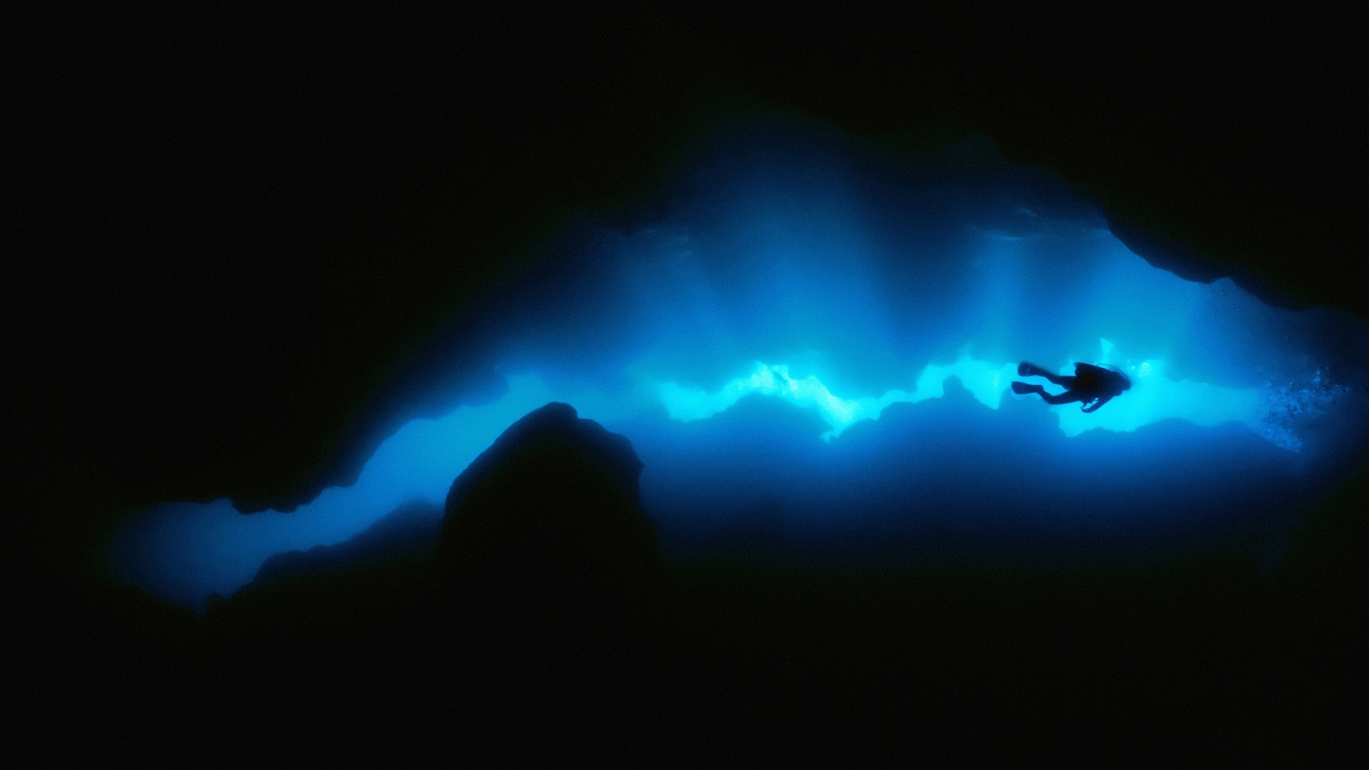 Scuba diver in a dark underwater cave with blue light HD Wallpaper
