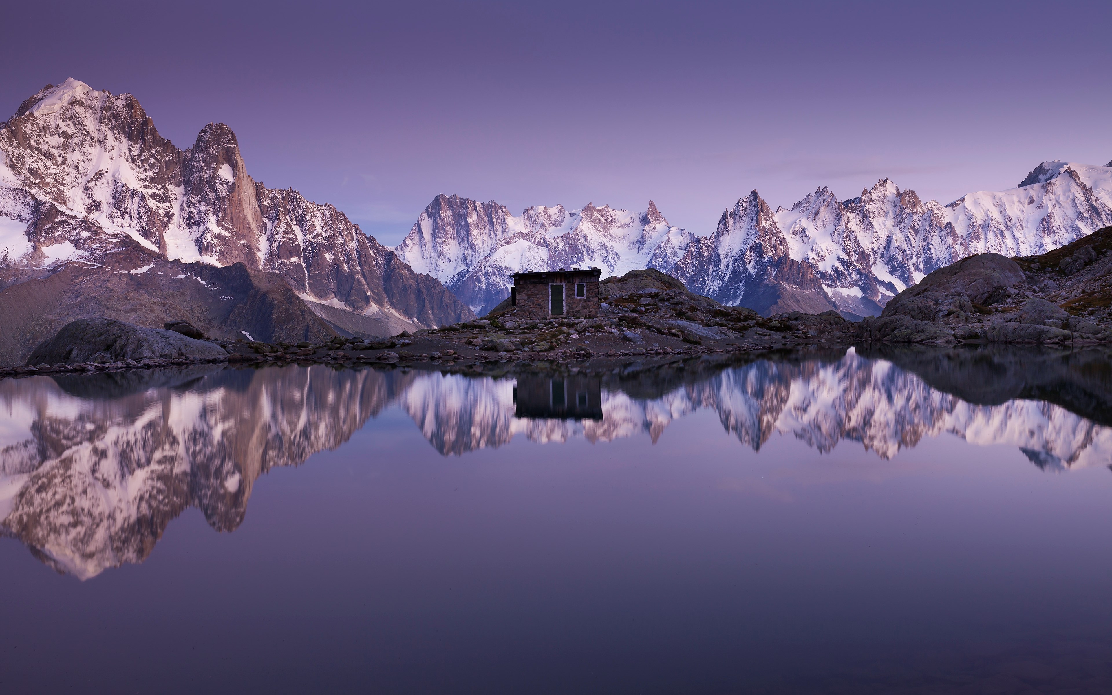 Cabin on rocky island with mountain reflection in lake HD Wallpaper