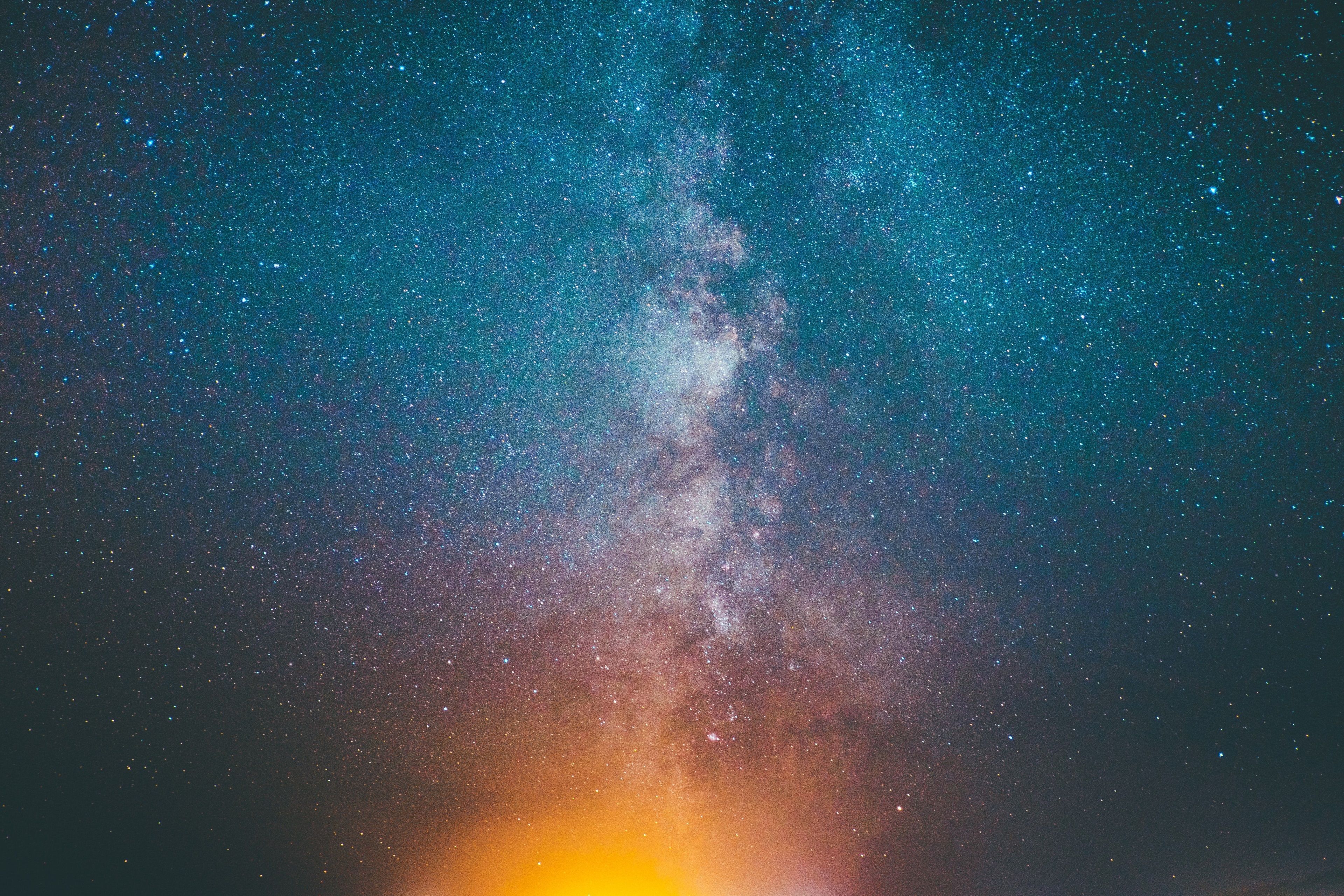 Milky Way galaxy with stars and orange glow HD Wallpaper