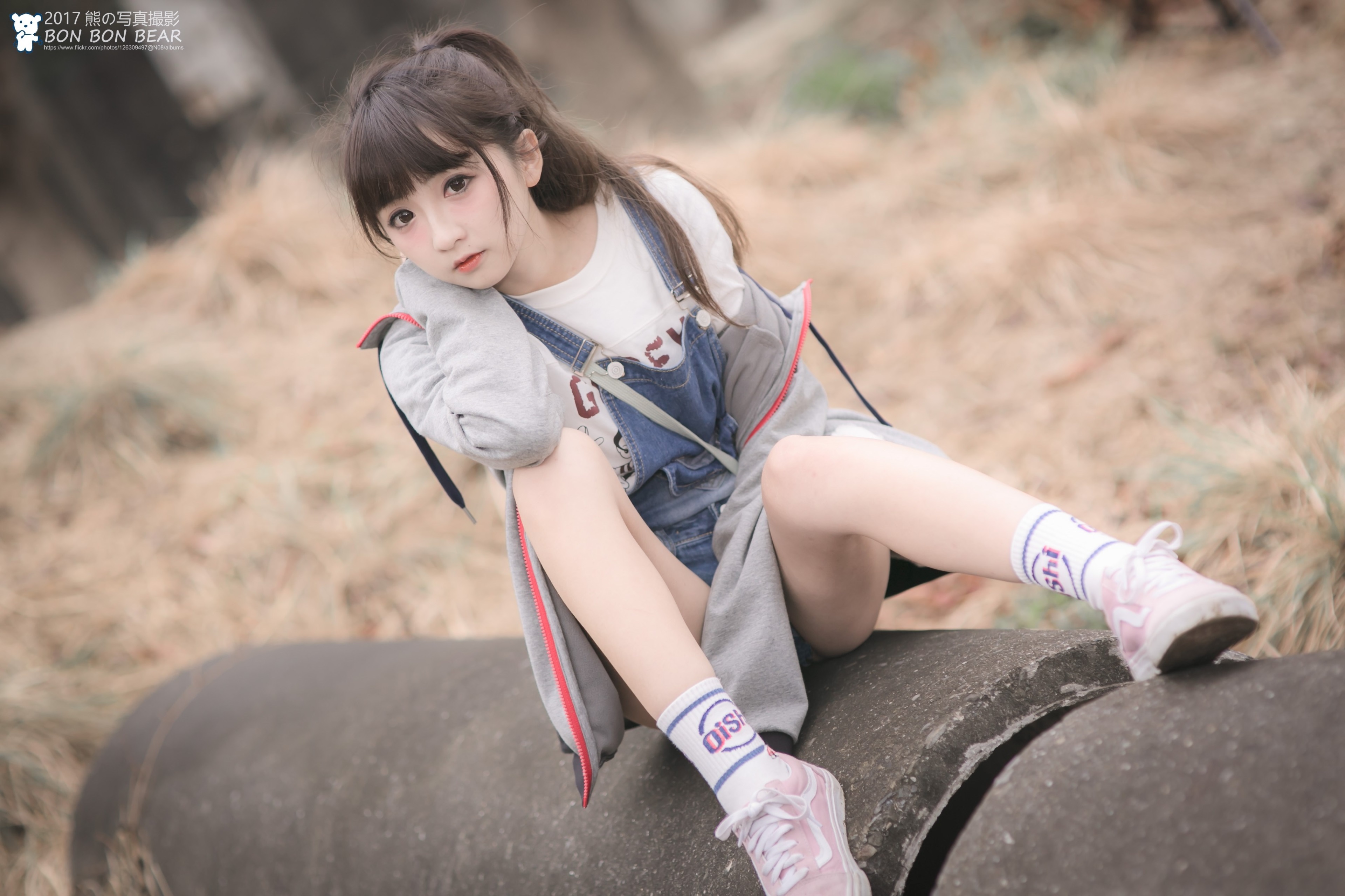 Asian girl in overalls sitting on a pipe HD Wallpaper