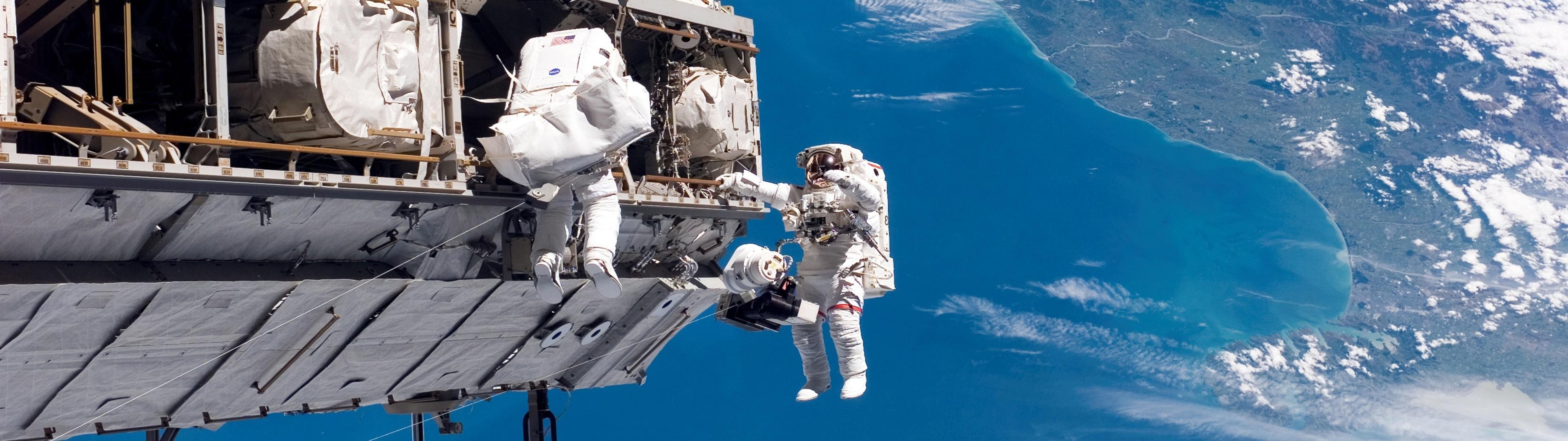 Astronauts performing spacewalk outside International Space Station over New Zealand HD Wallpaper
