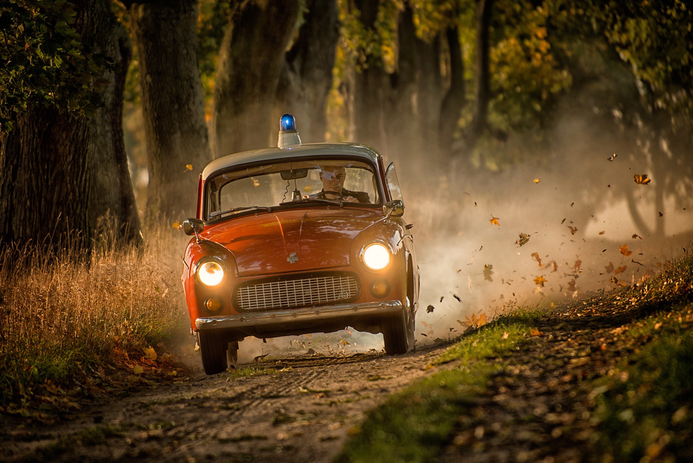 Orange Trabant car with blue light driving on dirt road HD Wallpaper