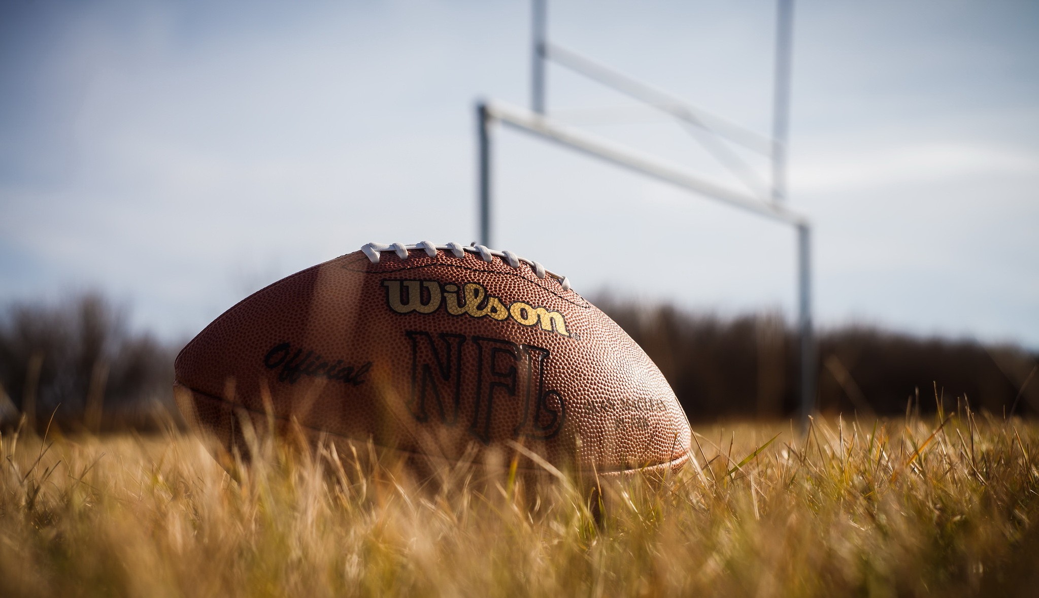 American football on grass with goalposts HD Wallpaper