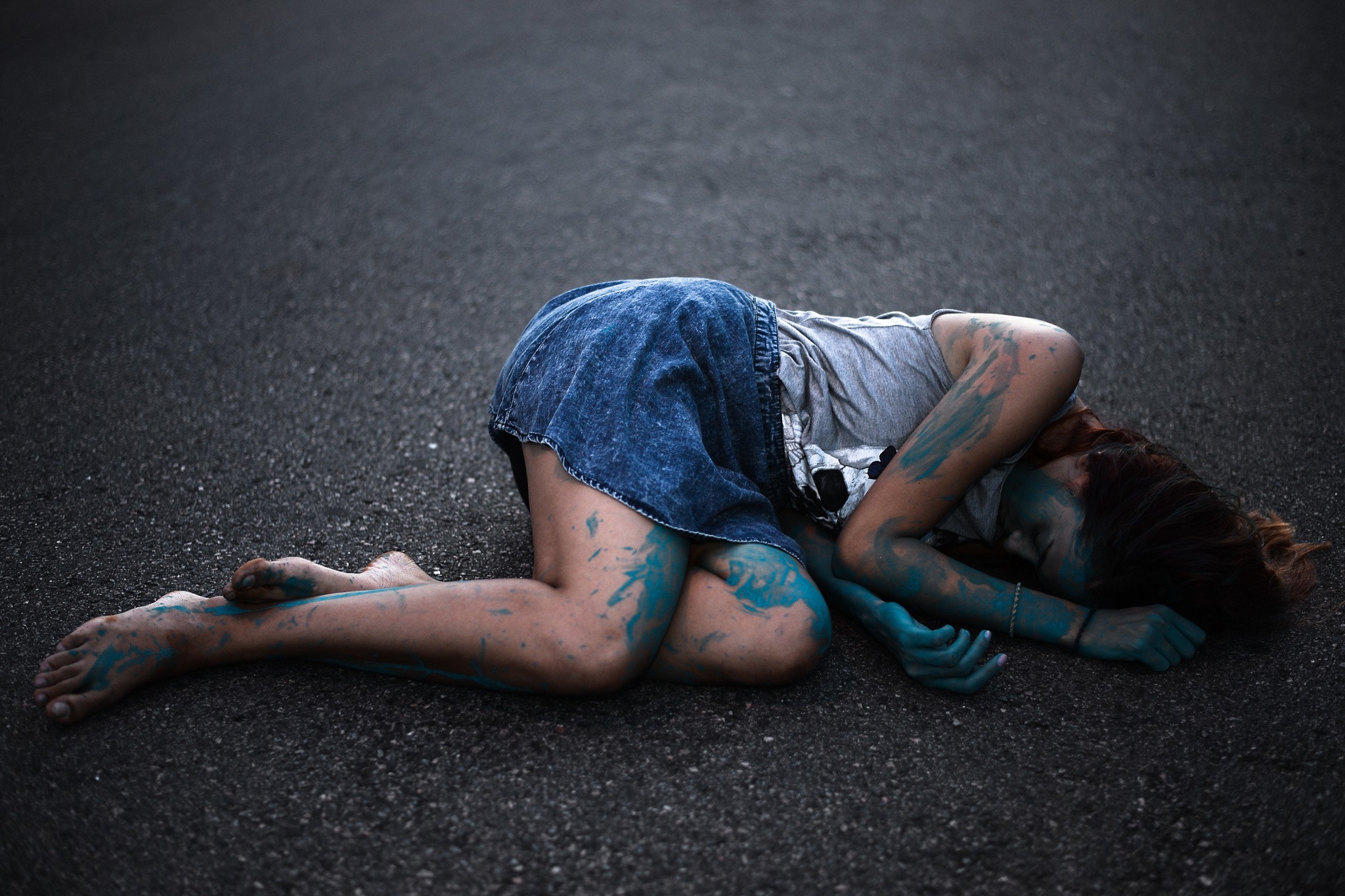 Woman with blue body paint lying on asphalt HD Wallpaper