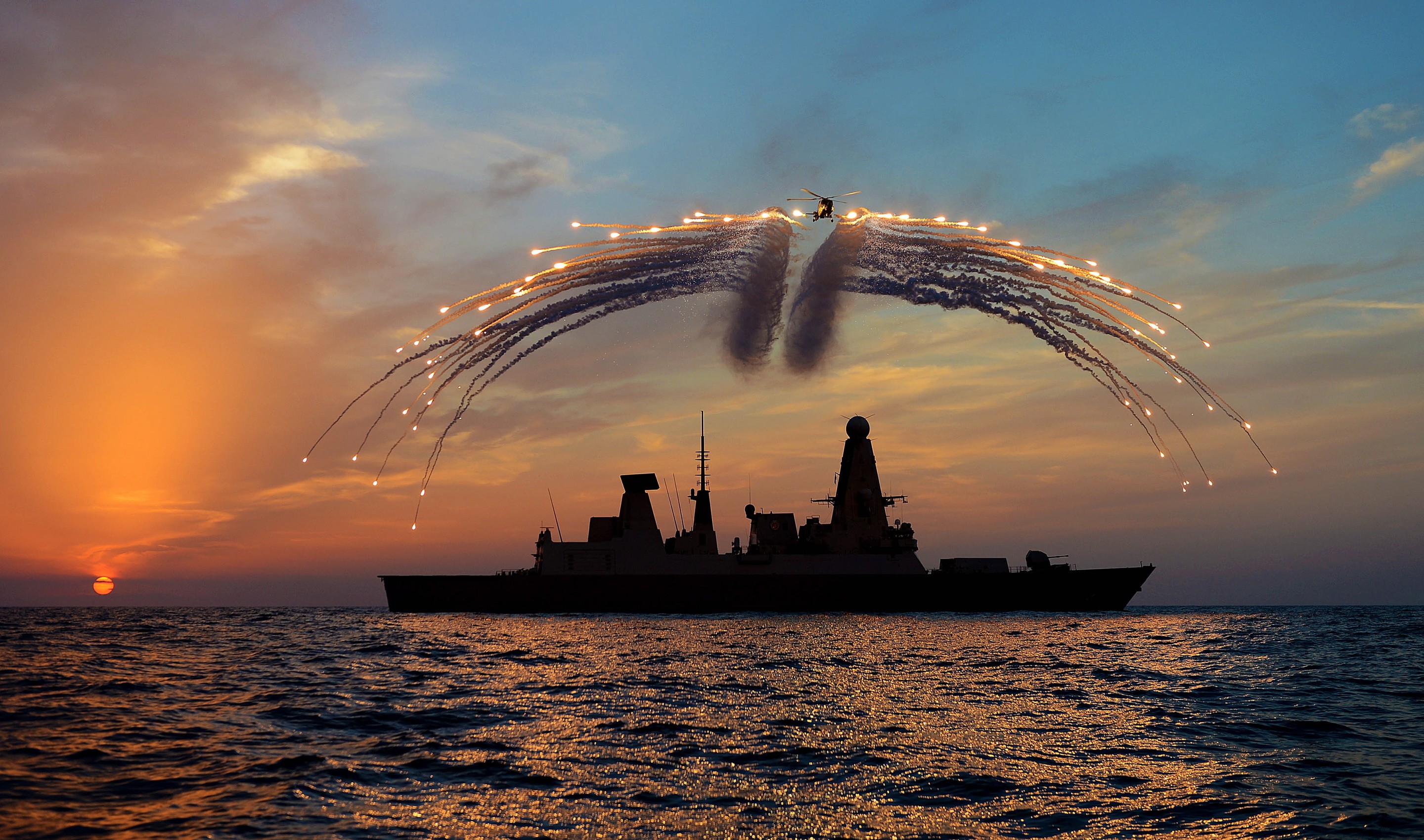 Royal Navy Type 45 destroyer firing flares at sunset HD Wallpaper