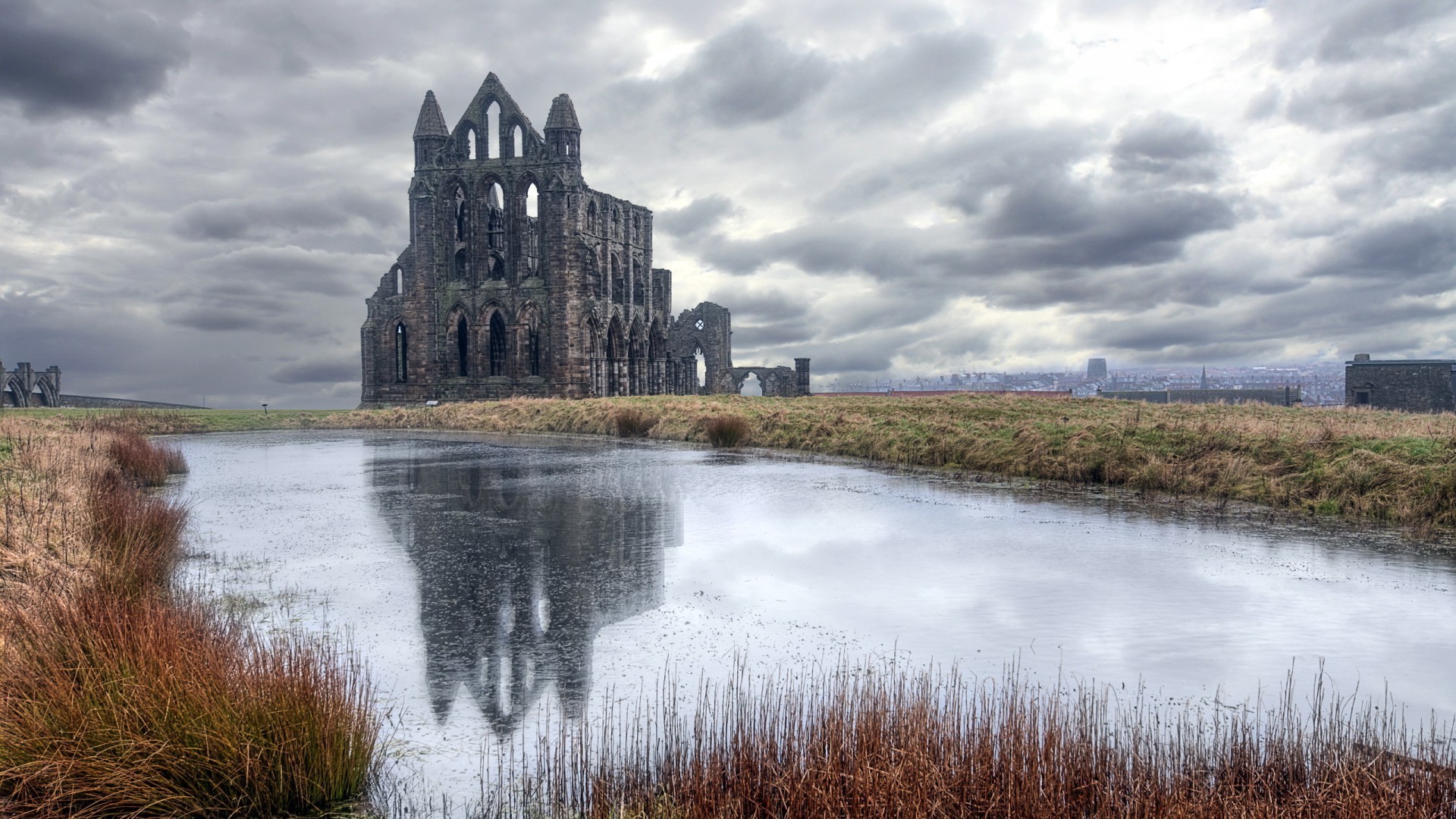 Whitby Abbey ruin reflection in pond under cloudy sky HD Wallpaper