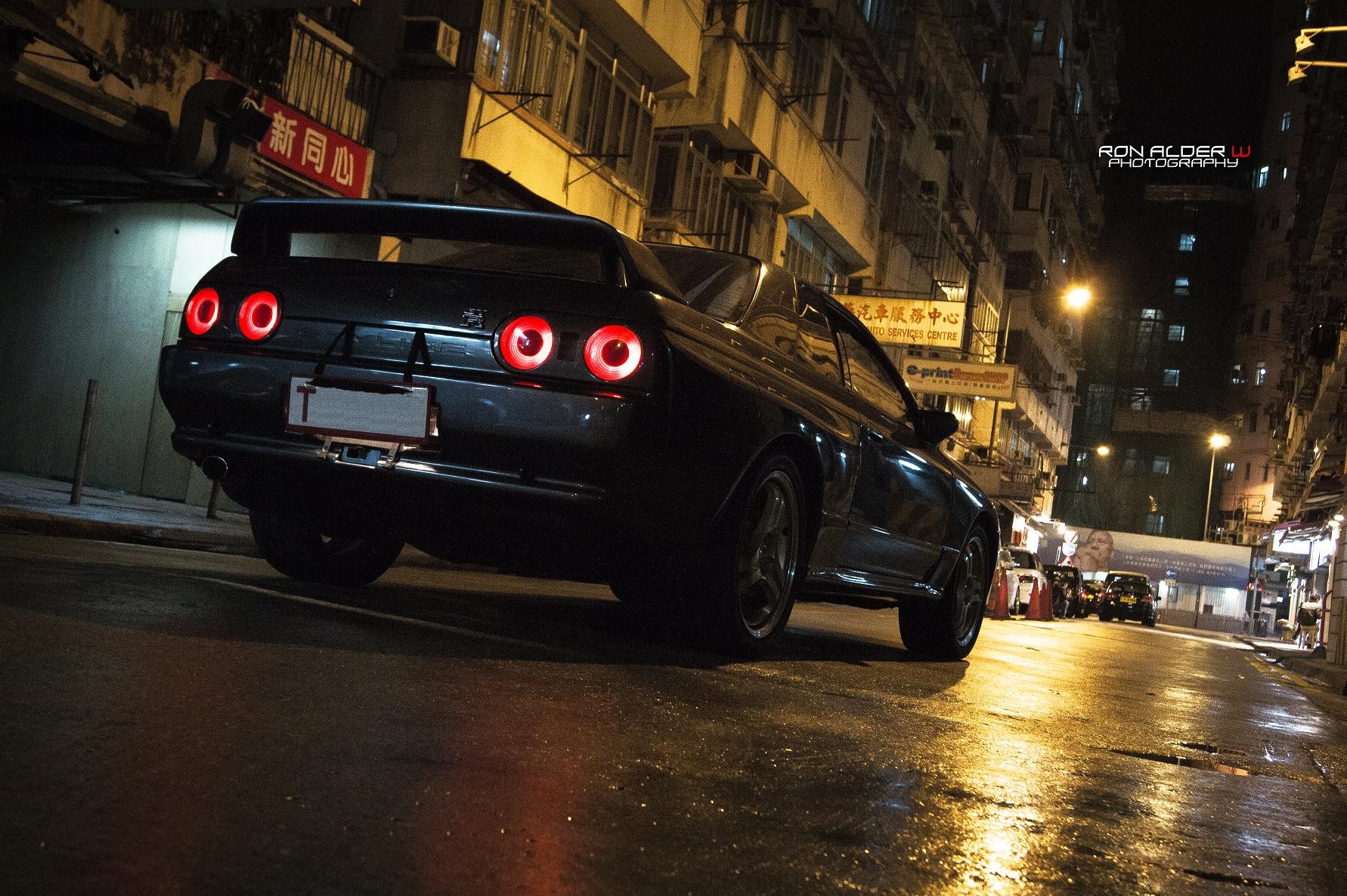 Nissan Skyline R32 GT-R parked on a wet city street at night HD Wallpaper