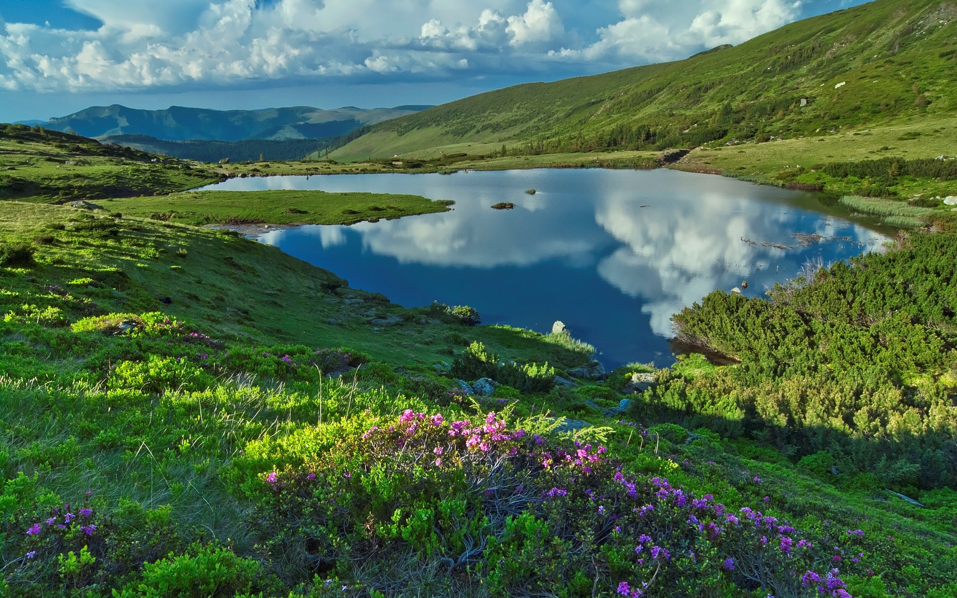 Mountain lake reflecting clouds and sky with green hills HD Wallpaper