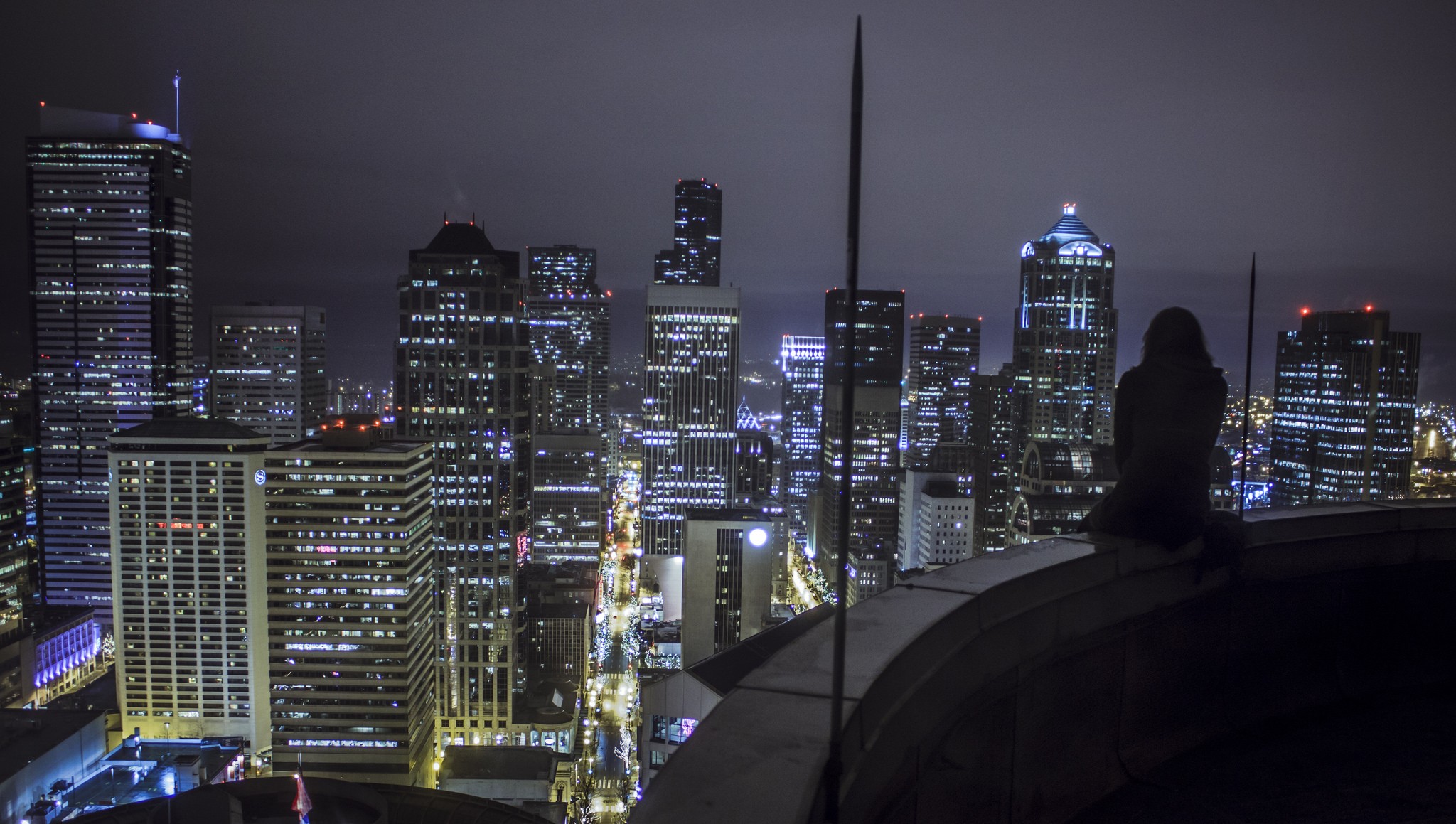 Woman on rooftop overlooking city at night HD Wallpaper