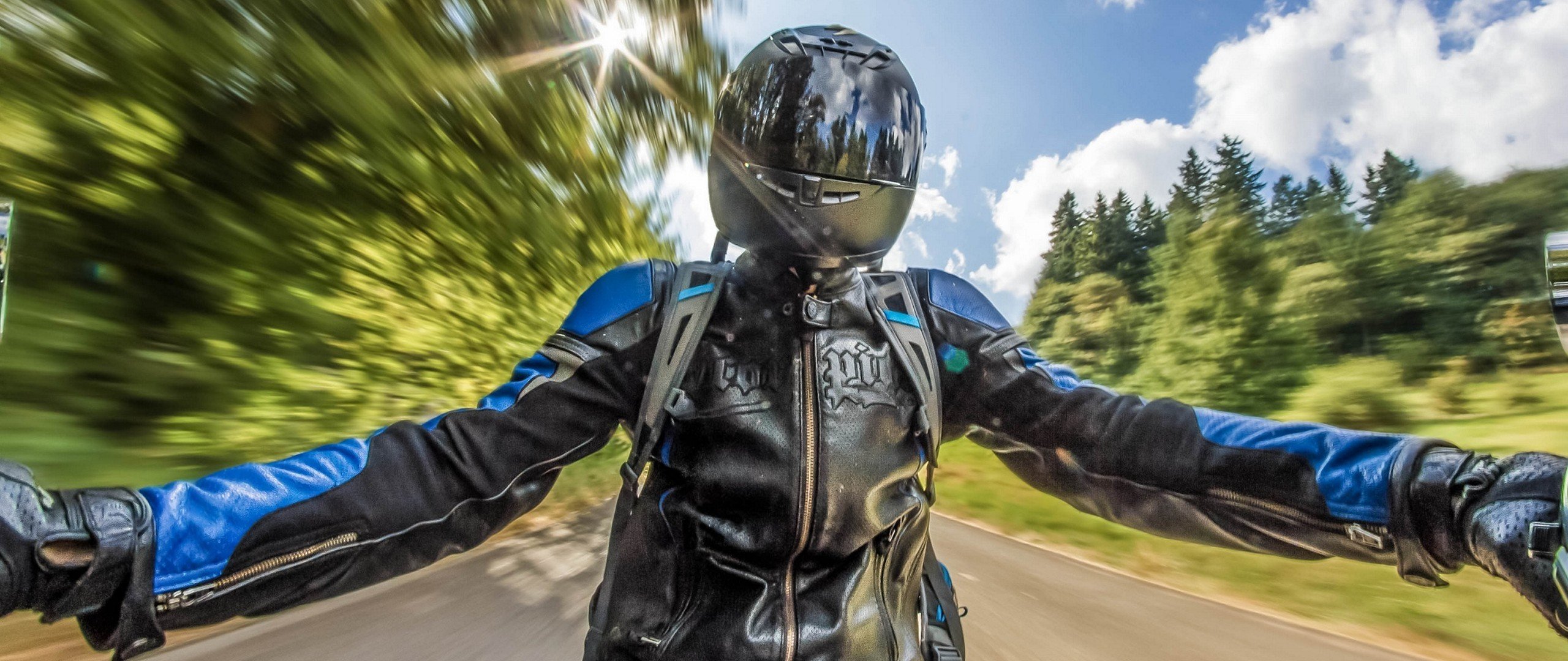 Motorcyclist wearing a black and blue jacket and helmet HD Wallpaper