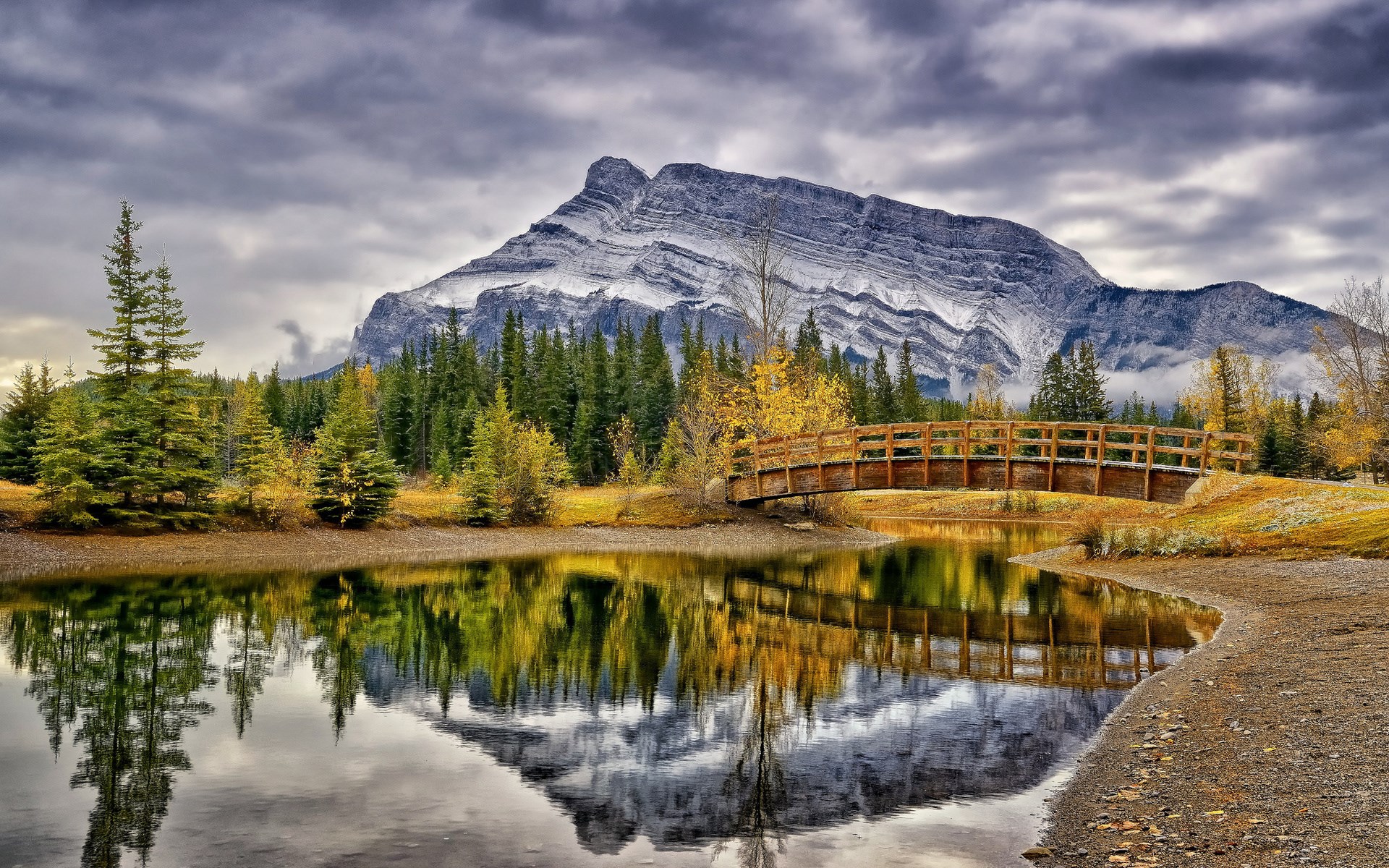 Mountain reflected in a lake with a wooden bridge HD Wallpaper