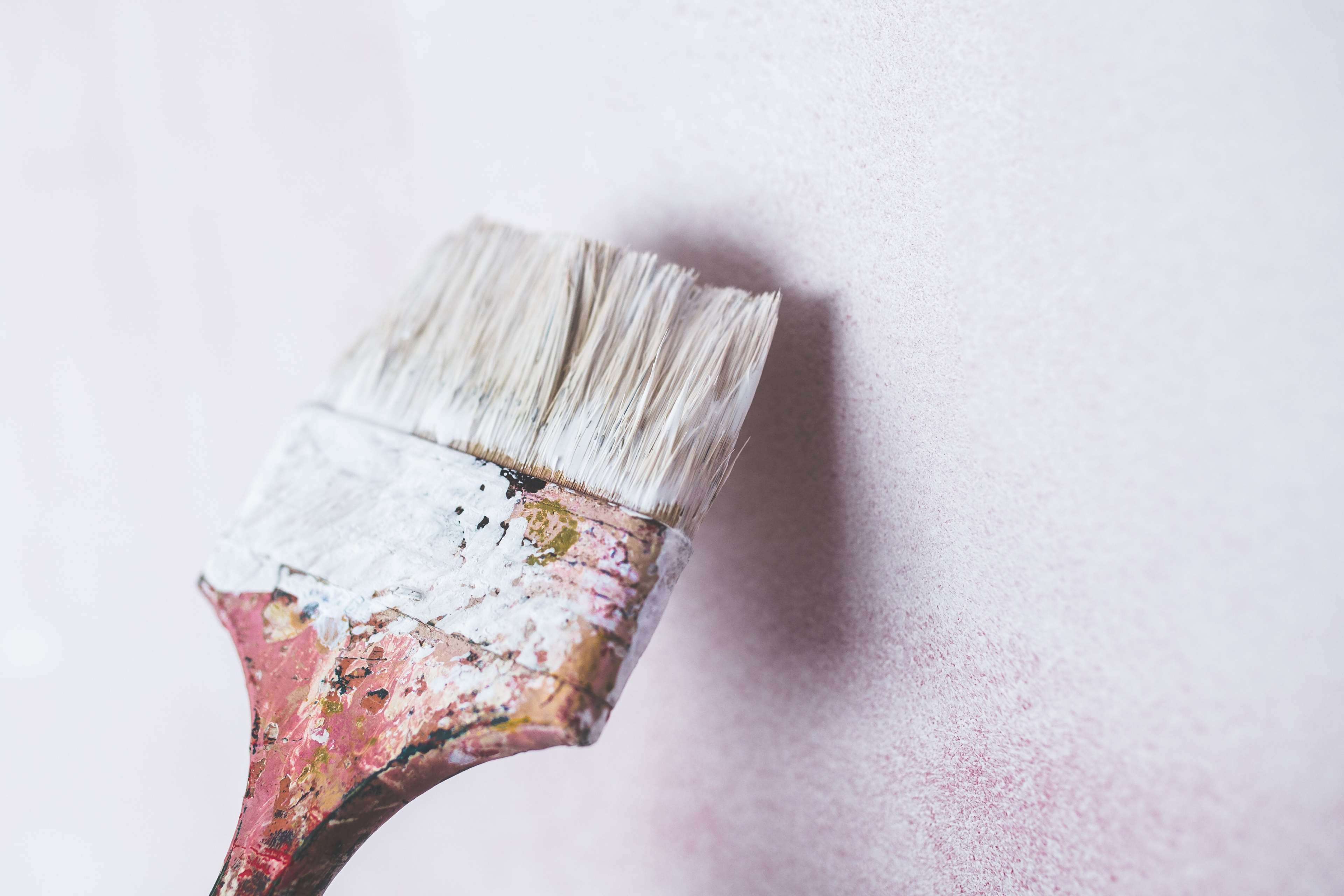 Paint brush with white paint on a textured wall HD Wallpaper
