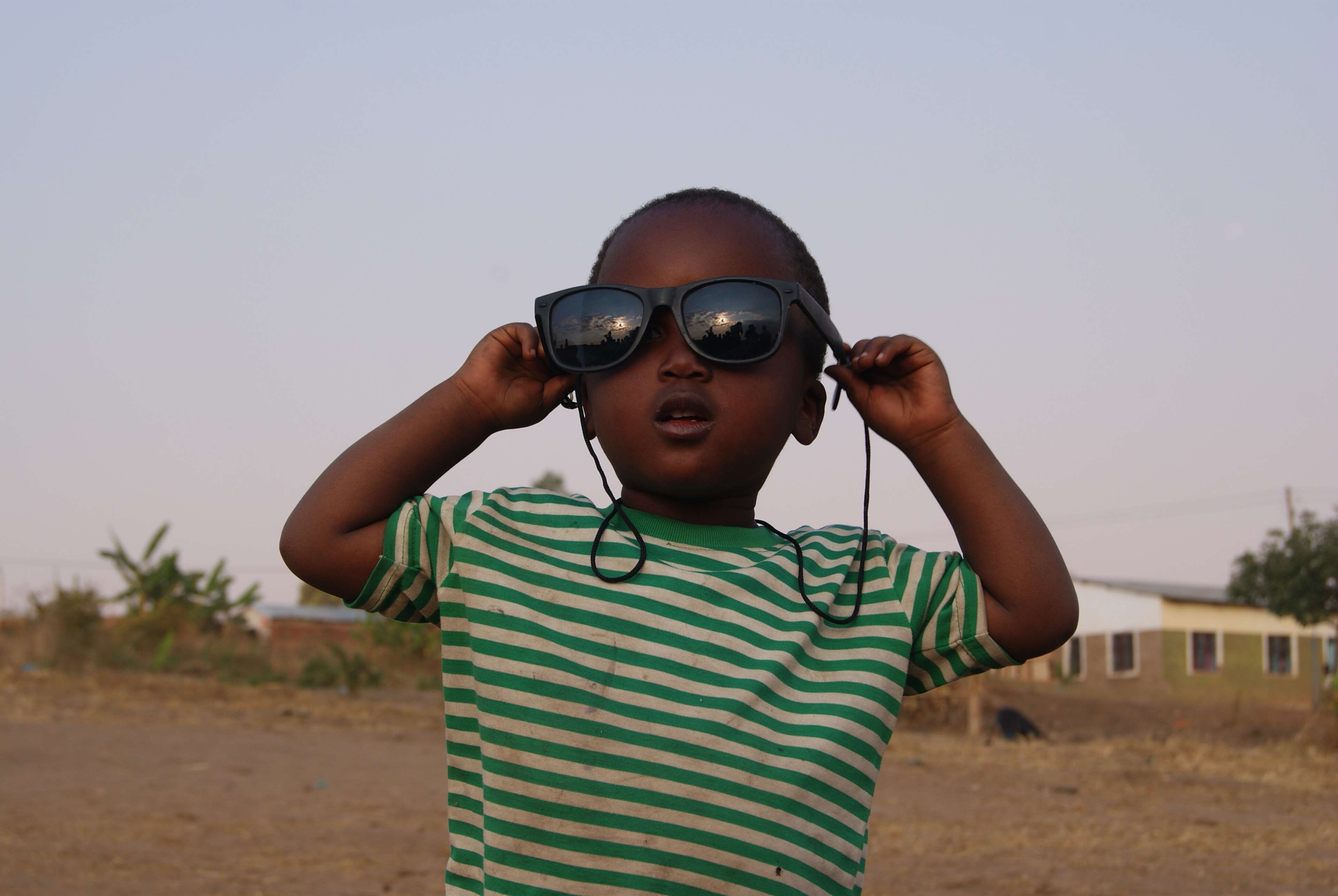 Child wearing sunglasses at sunset in Africa HD Wallpaper