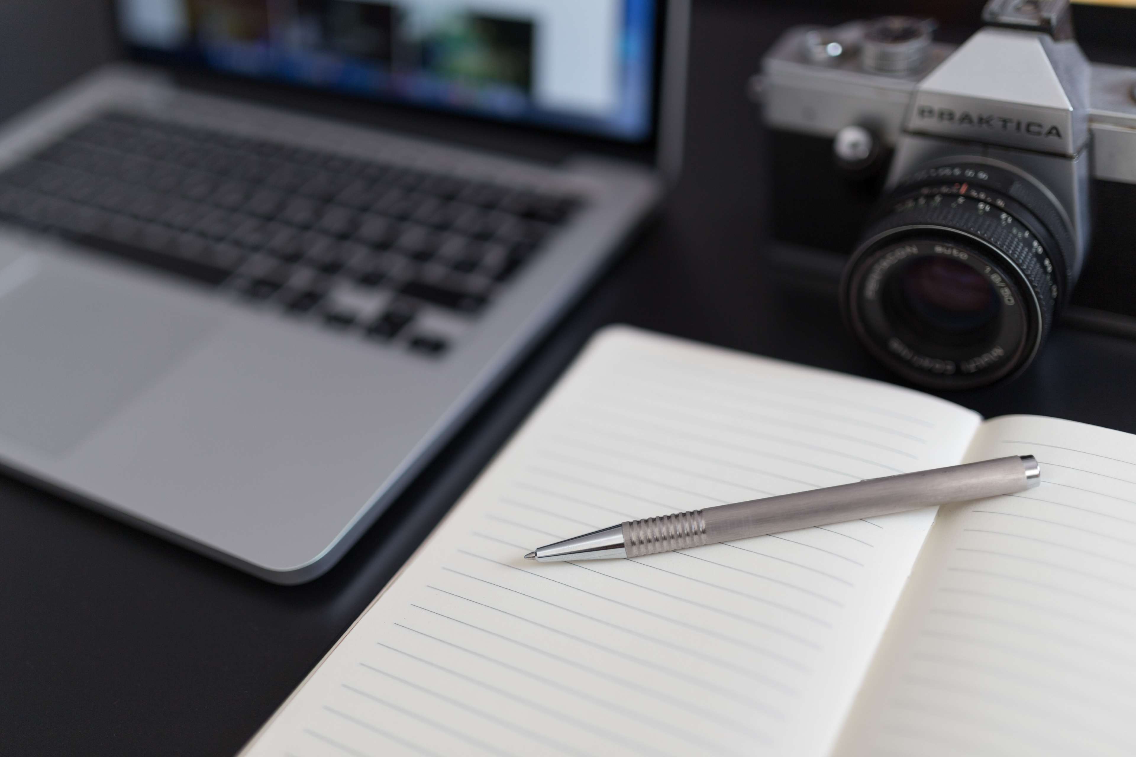 Laptop, Camera, Notebook, and Pen on Desk HD Wallpaper