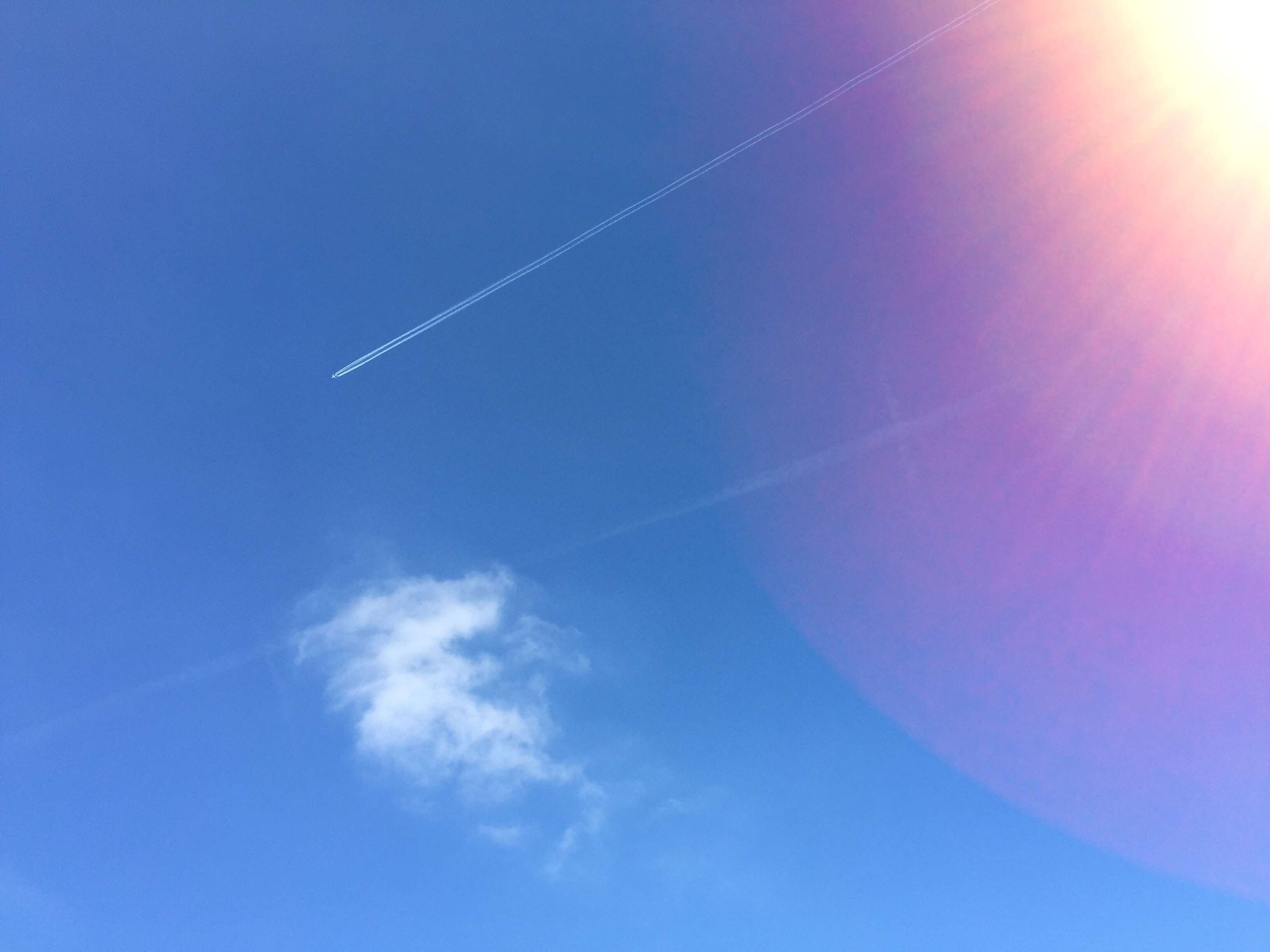 Airplane contrail in a bright blue sky with sun flare HD Wallpaper