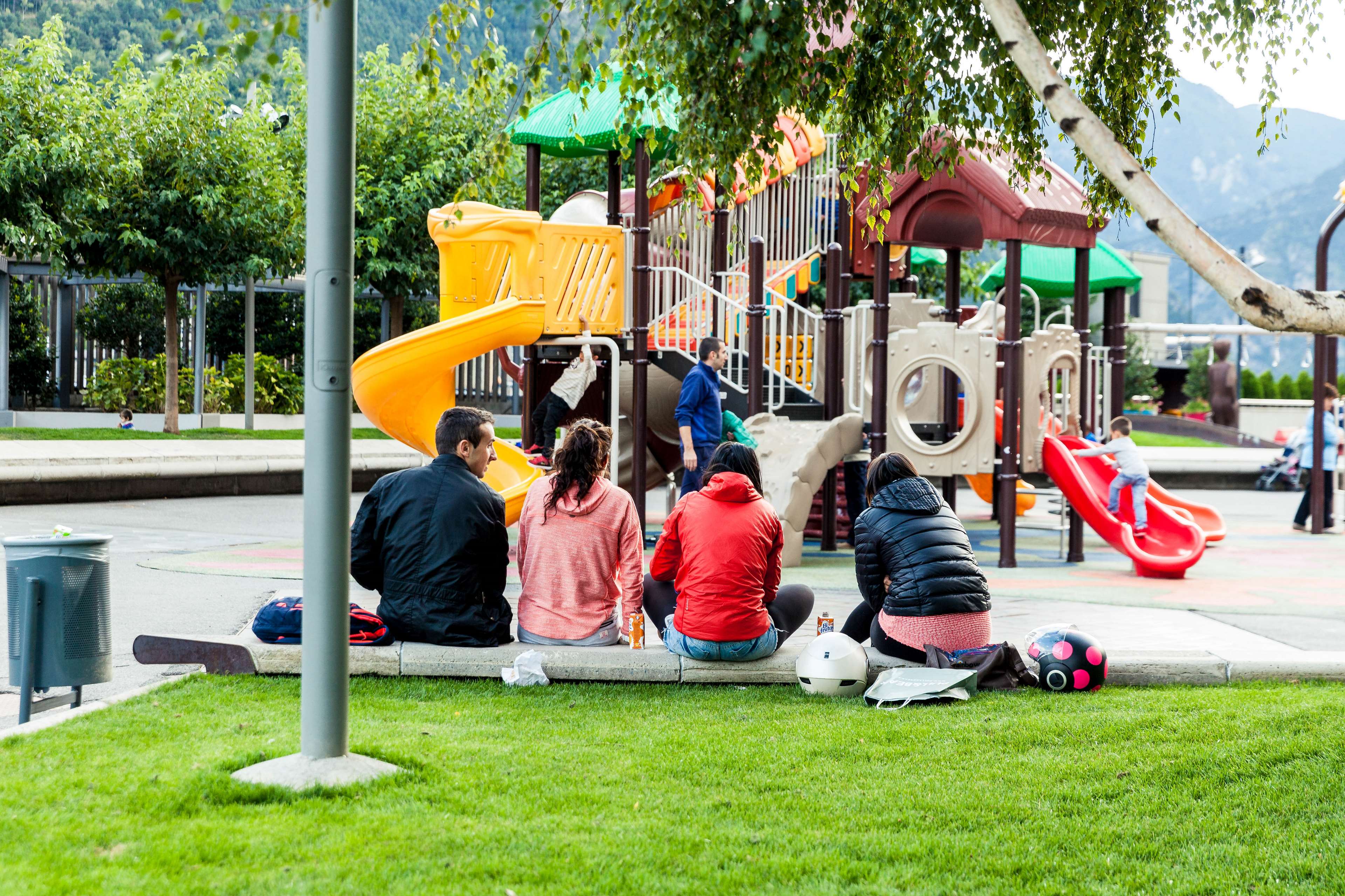 People sitting at a playground with mountains in the background HD Wallpaper