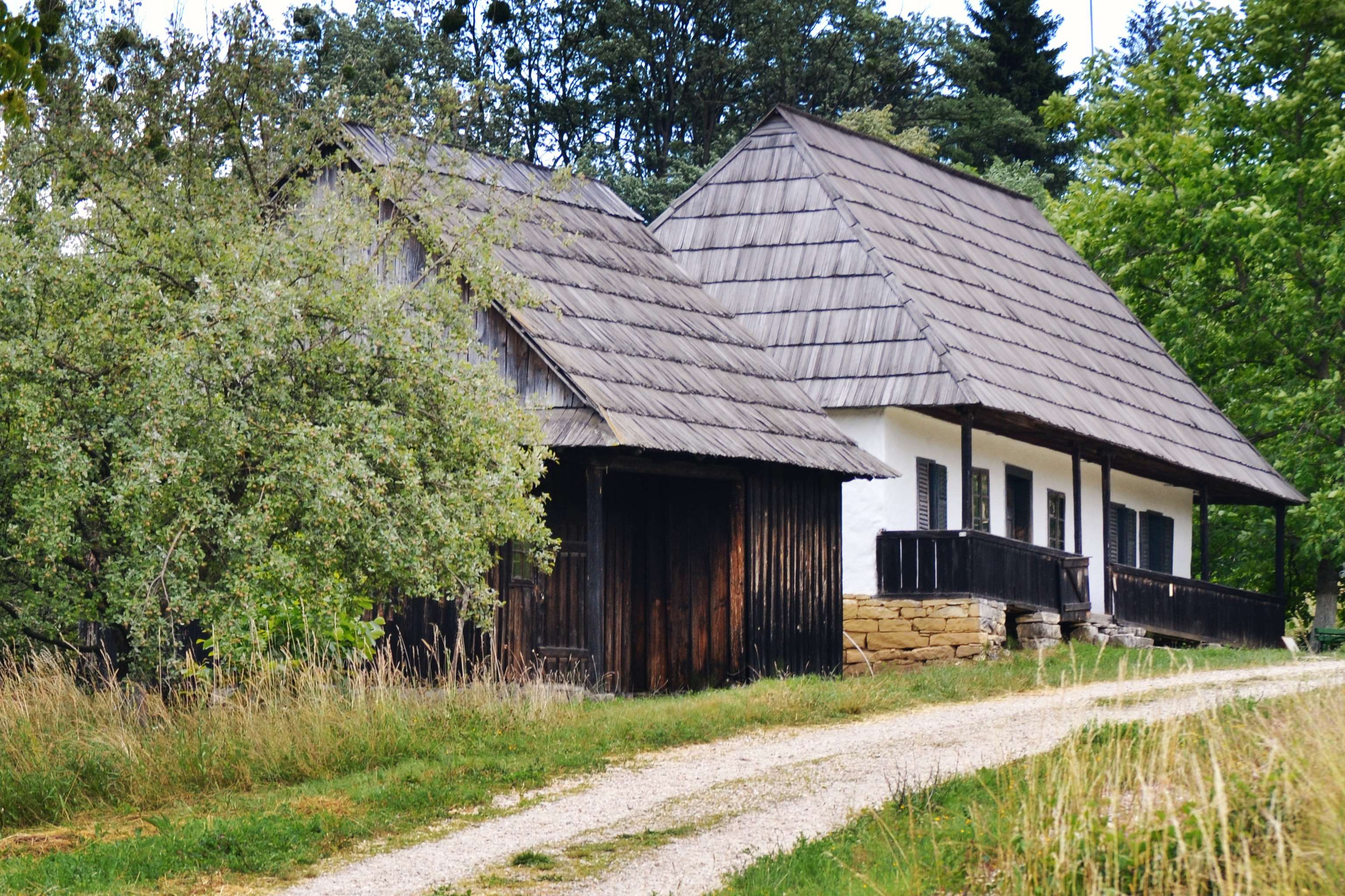 Rustic wooden house with a shingled roof in a grassy field HD Wallpaper