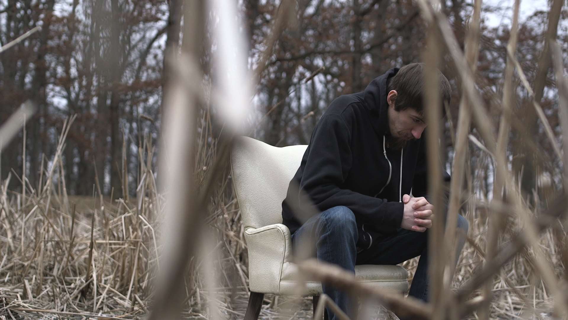 Man sitting on a chair in a dry field HD Wallpaper