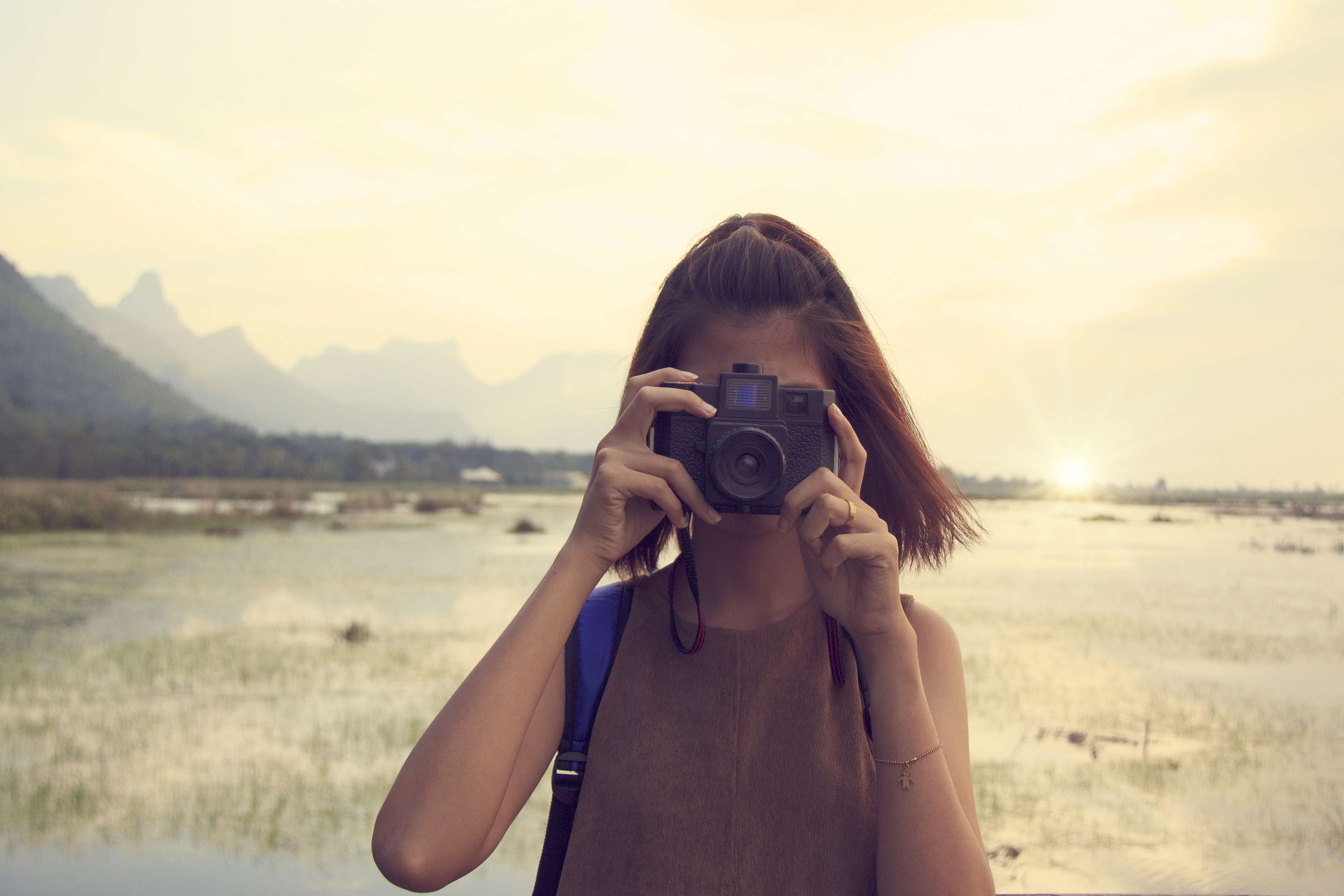 Woman taking a photo with a camera at sunset HD Wallpaper