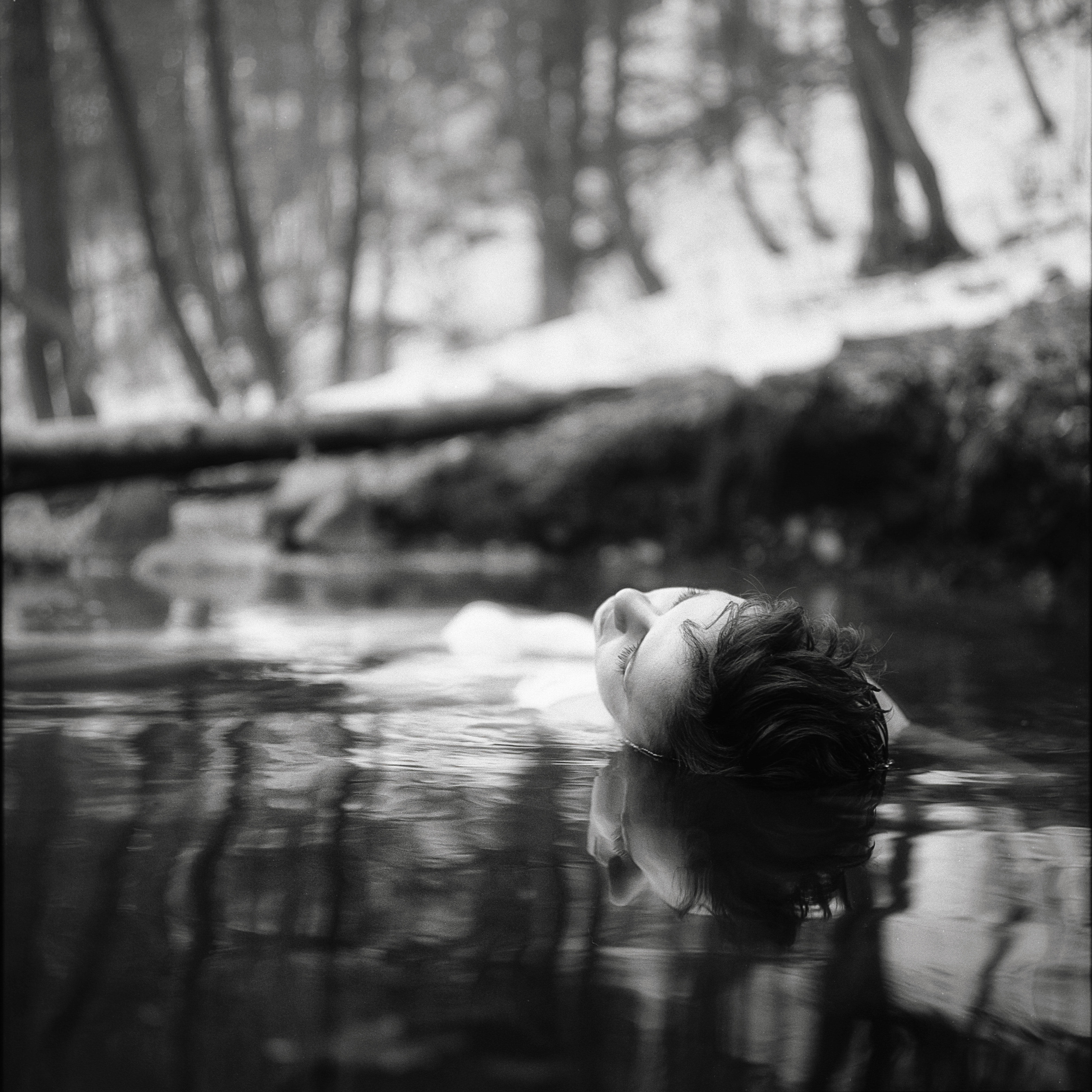 Woman floating in water in a forest HD Wallpaper