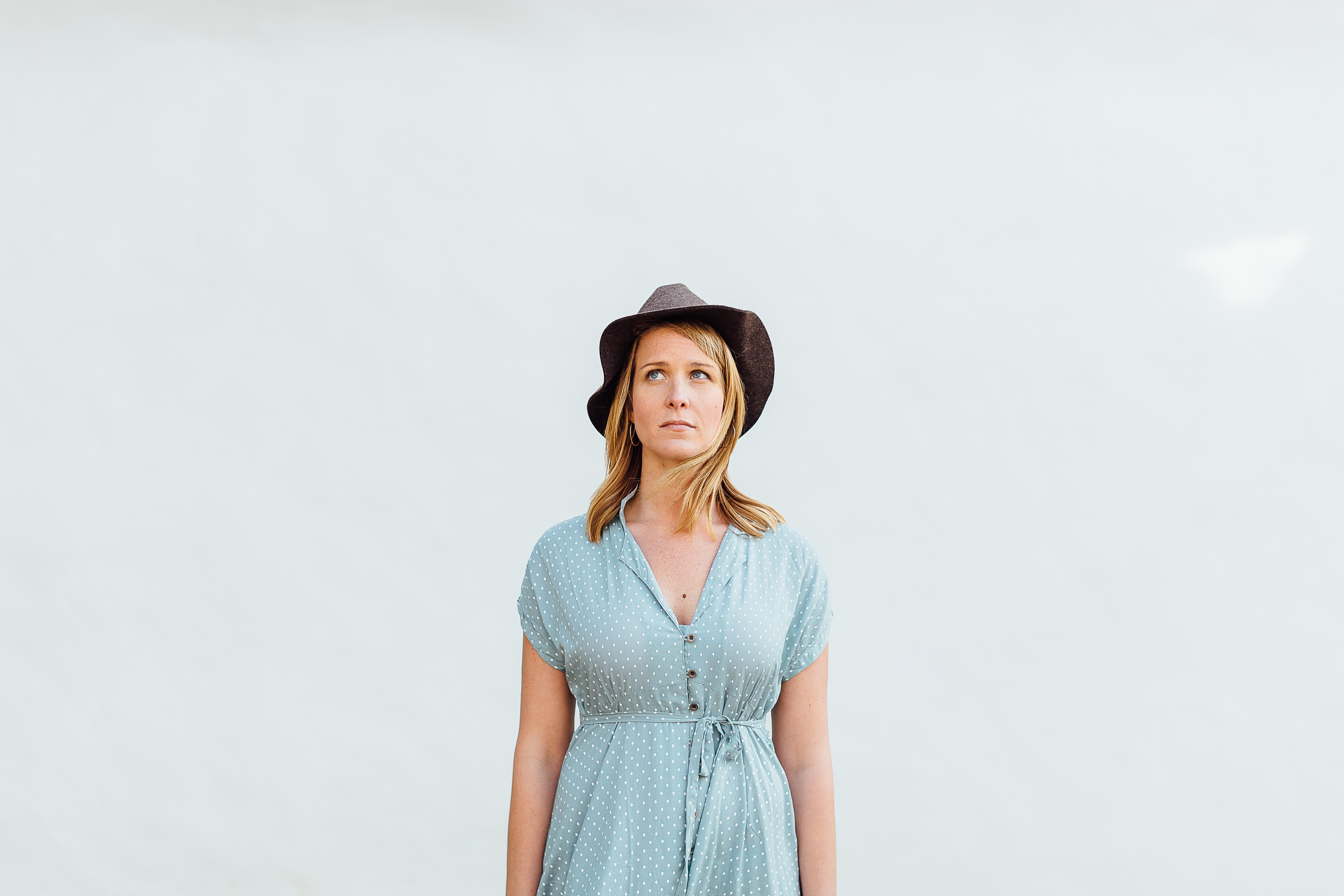 Woman in polka dot dress and hat looking up HD Wallpaper