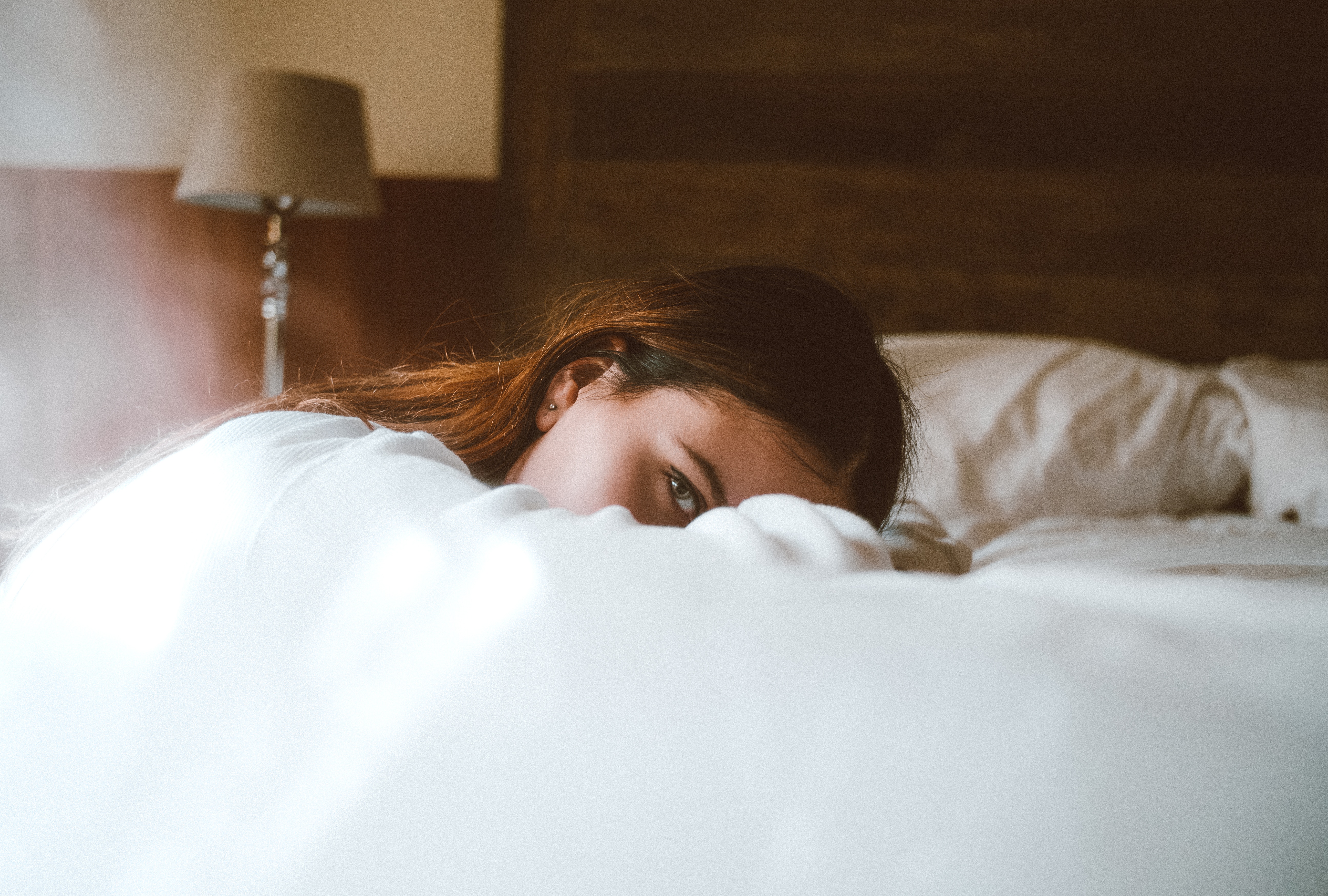 Young woman laying in bed with lamp in background HD Wallpaper