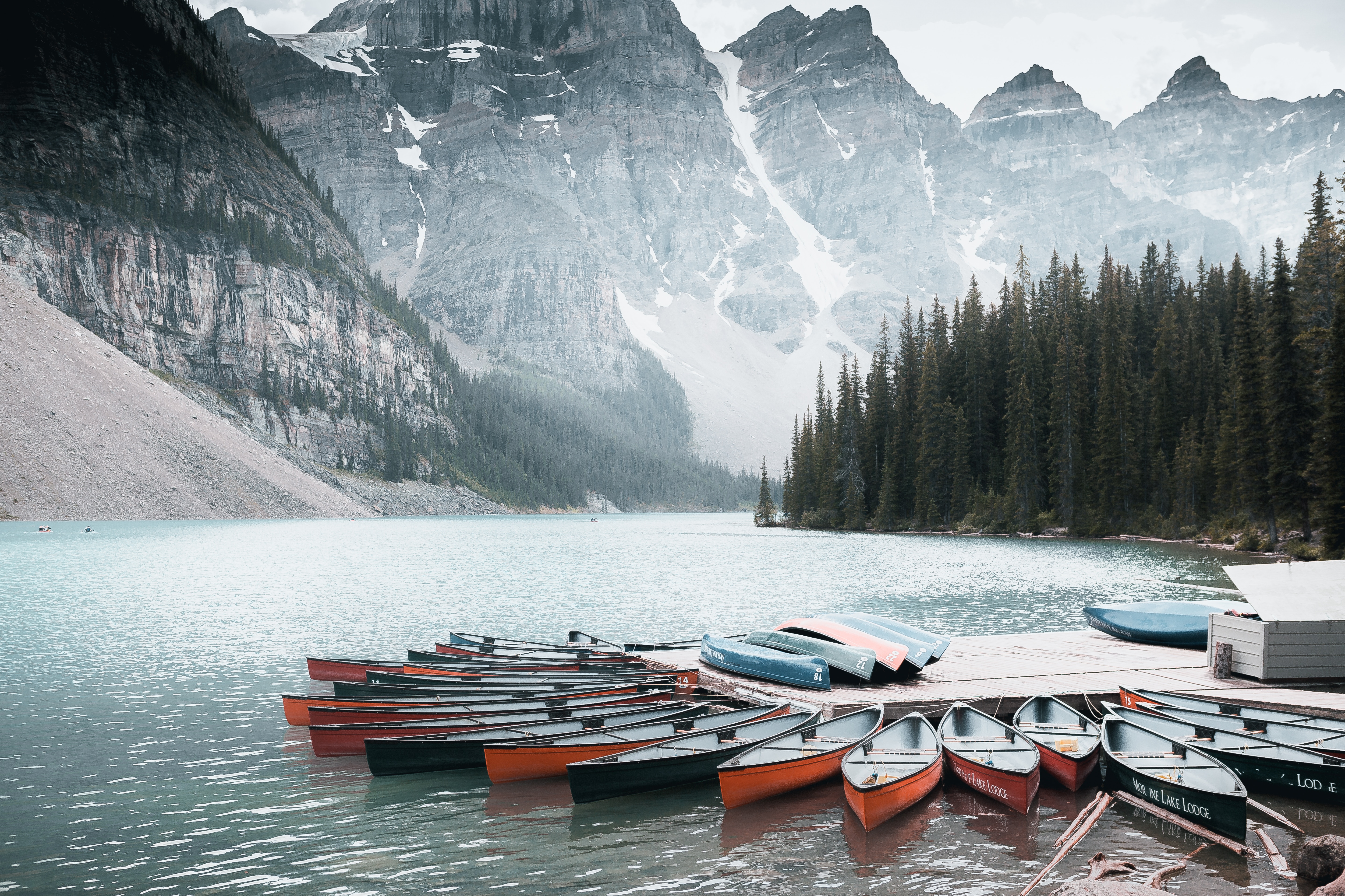 Canoes docked on Moraine Lake with mountains in background HD Wallpaper