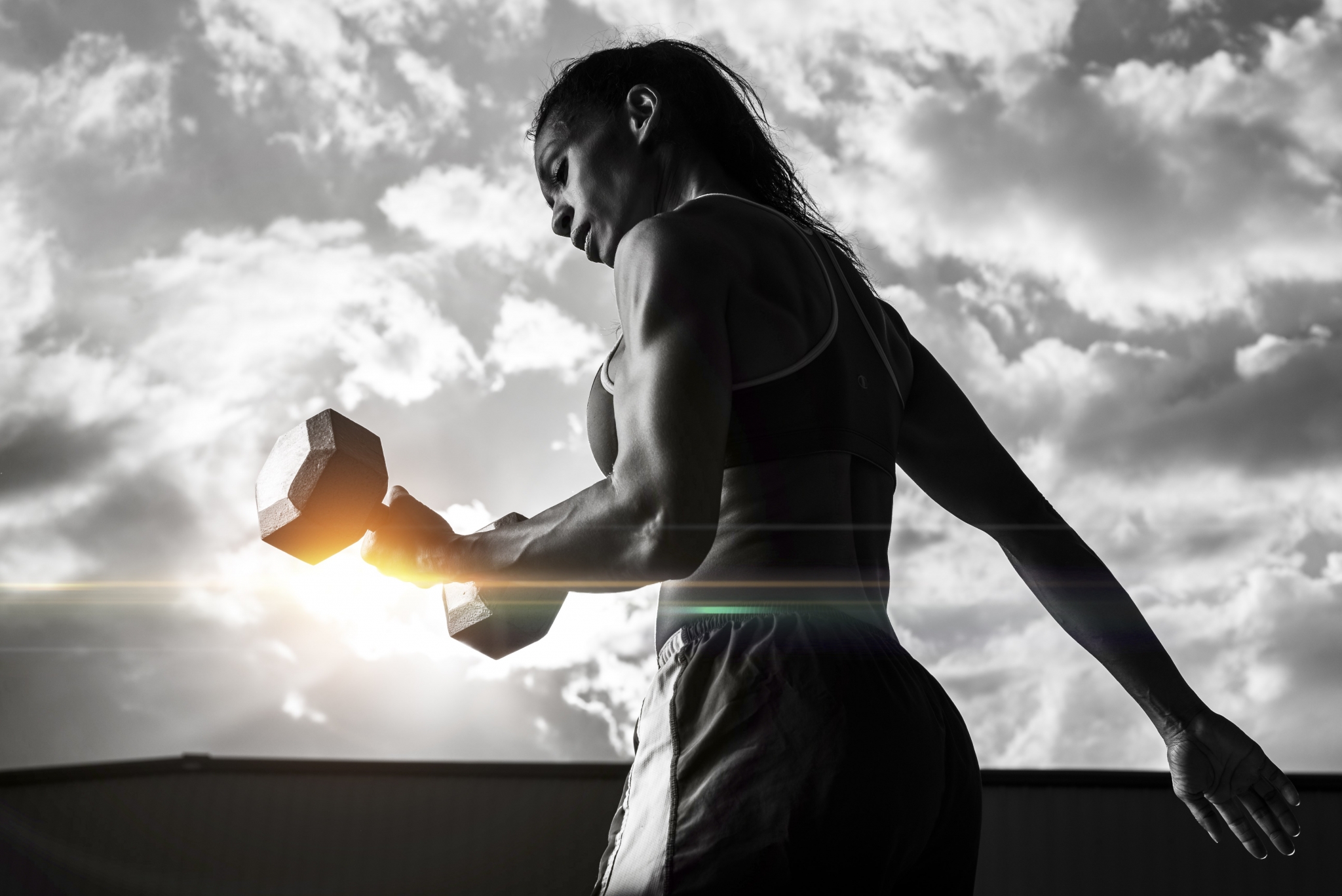 Woman lifting dumbbell against cloudy sky HD Wallpaper