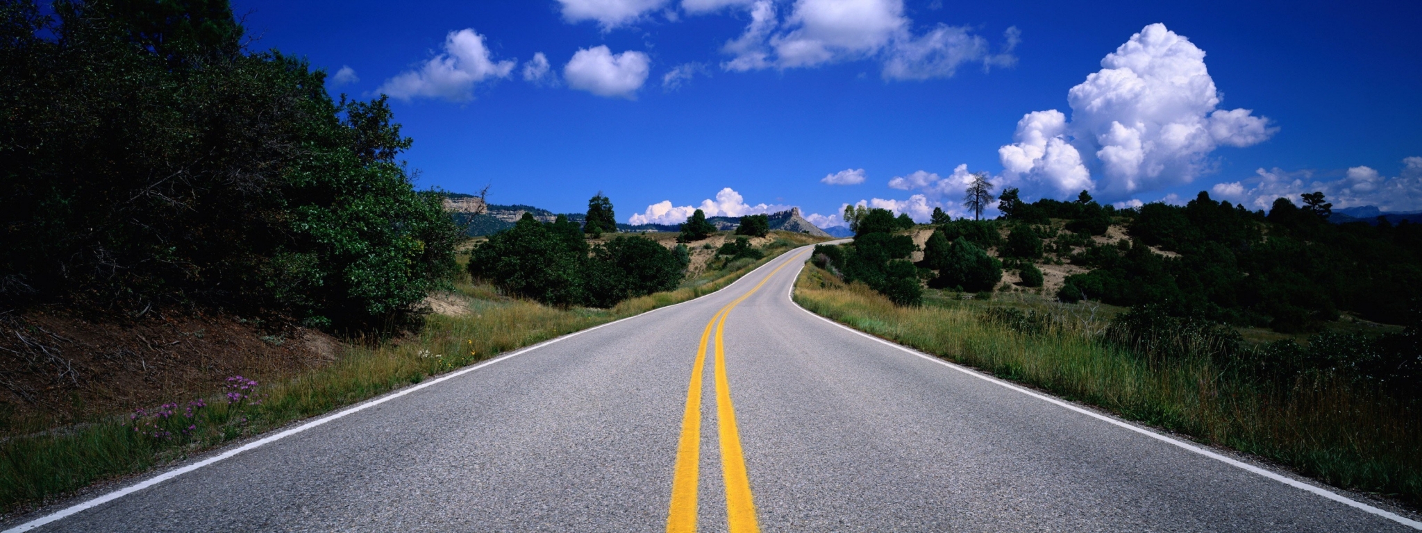 Scenic Road Winding Through Hills Under Blue Sky HD Wallpaper