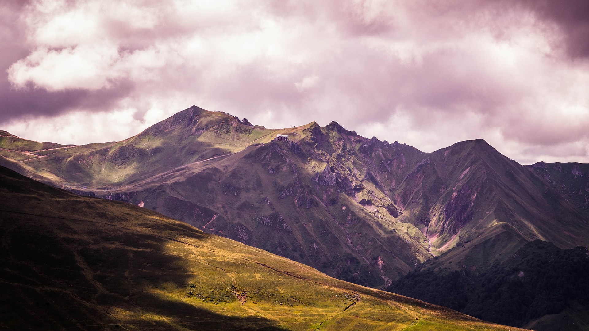 Mountain range with building on peak under cloudy sky HD Wallpaper