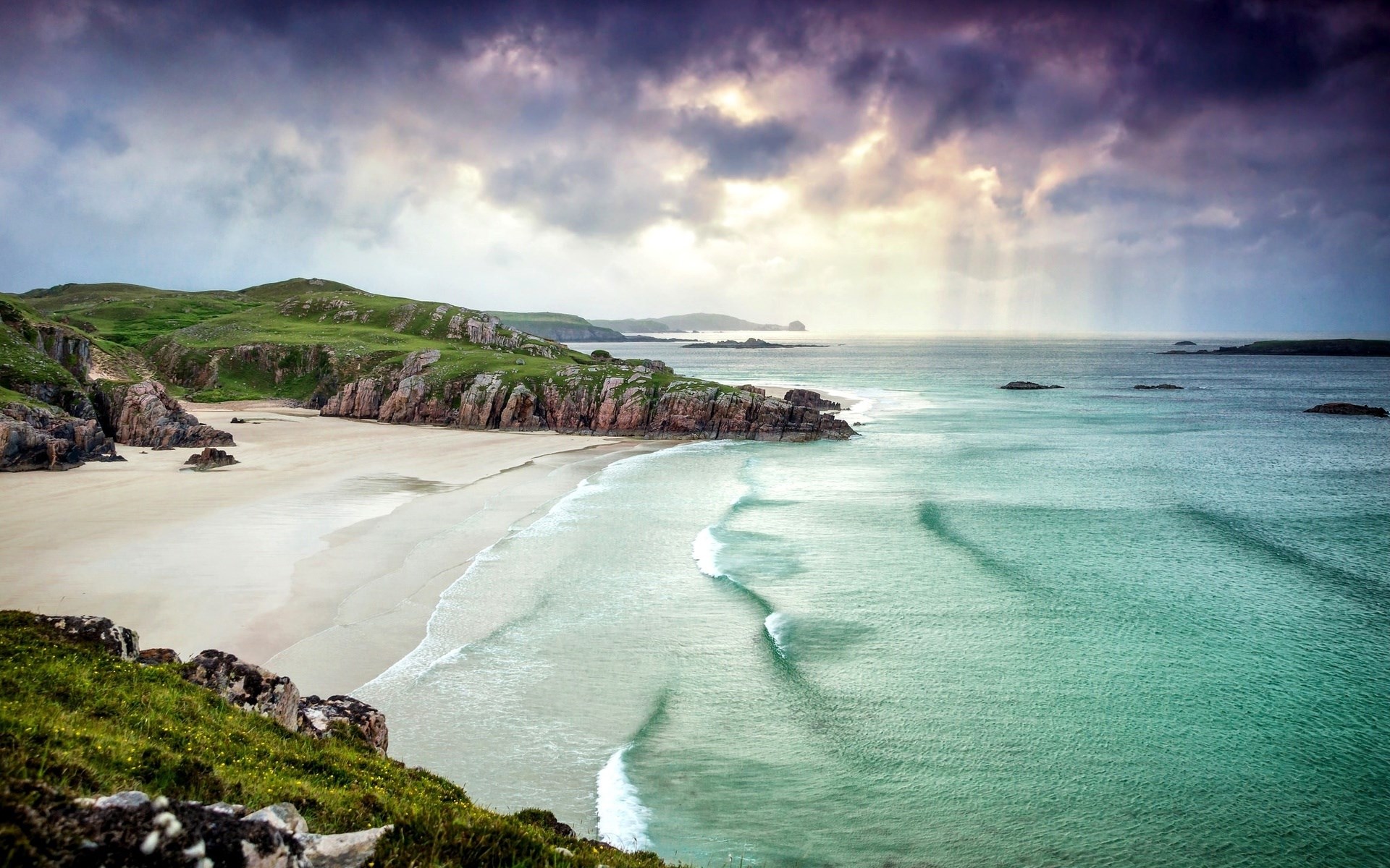 Dramatic clouds over a rugged coastline and beach HD Wallpaper
