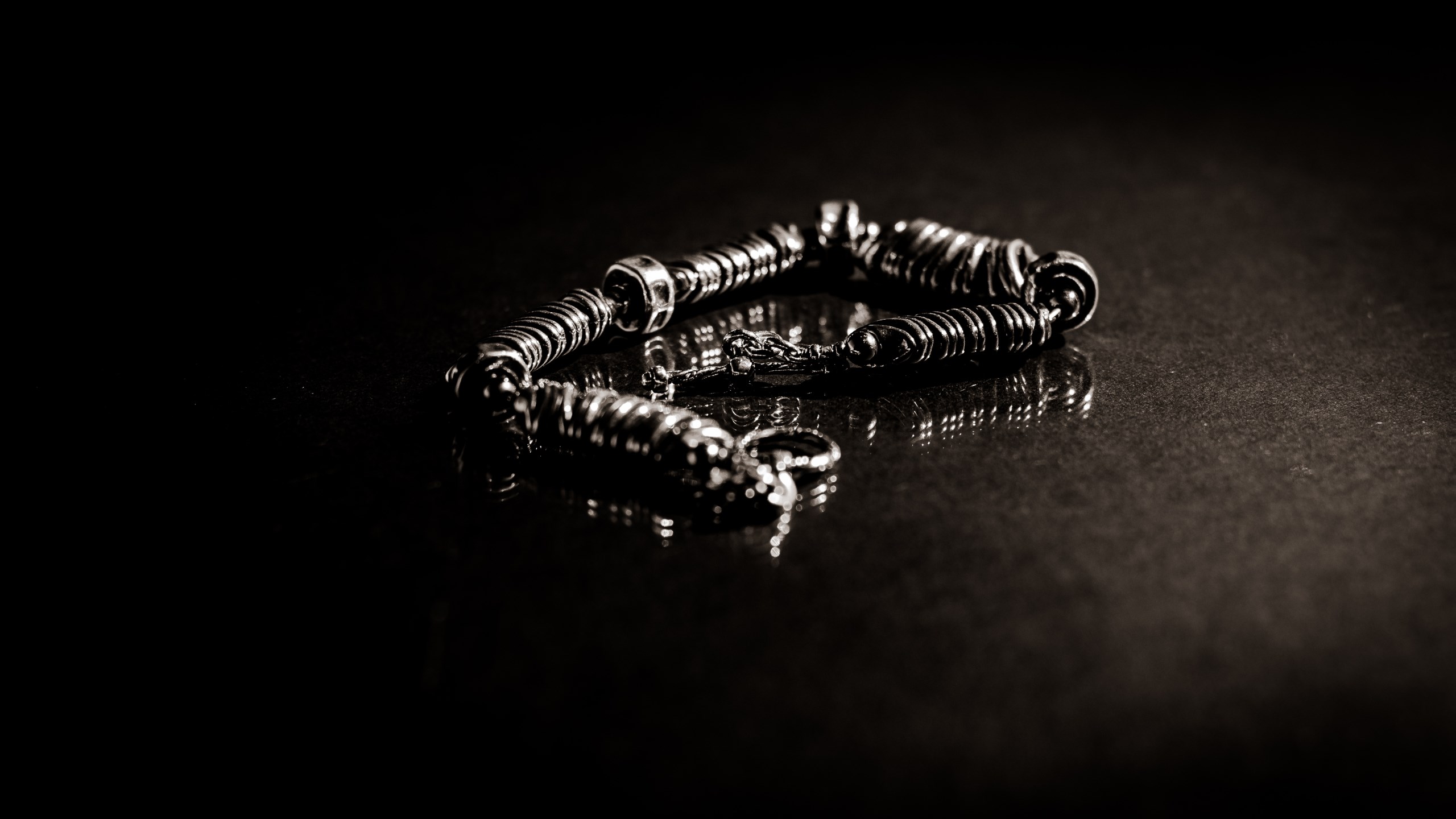 Silver bracelet with coiled links on a dark surface HD Wallpaper