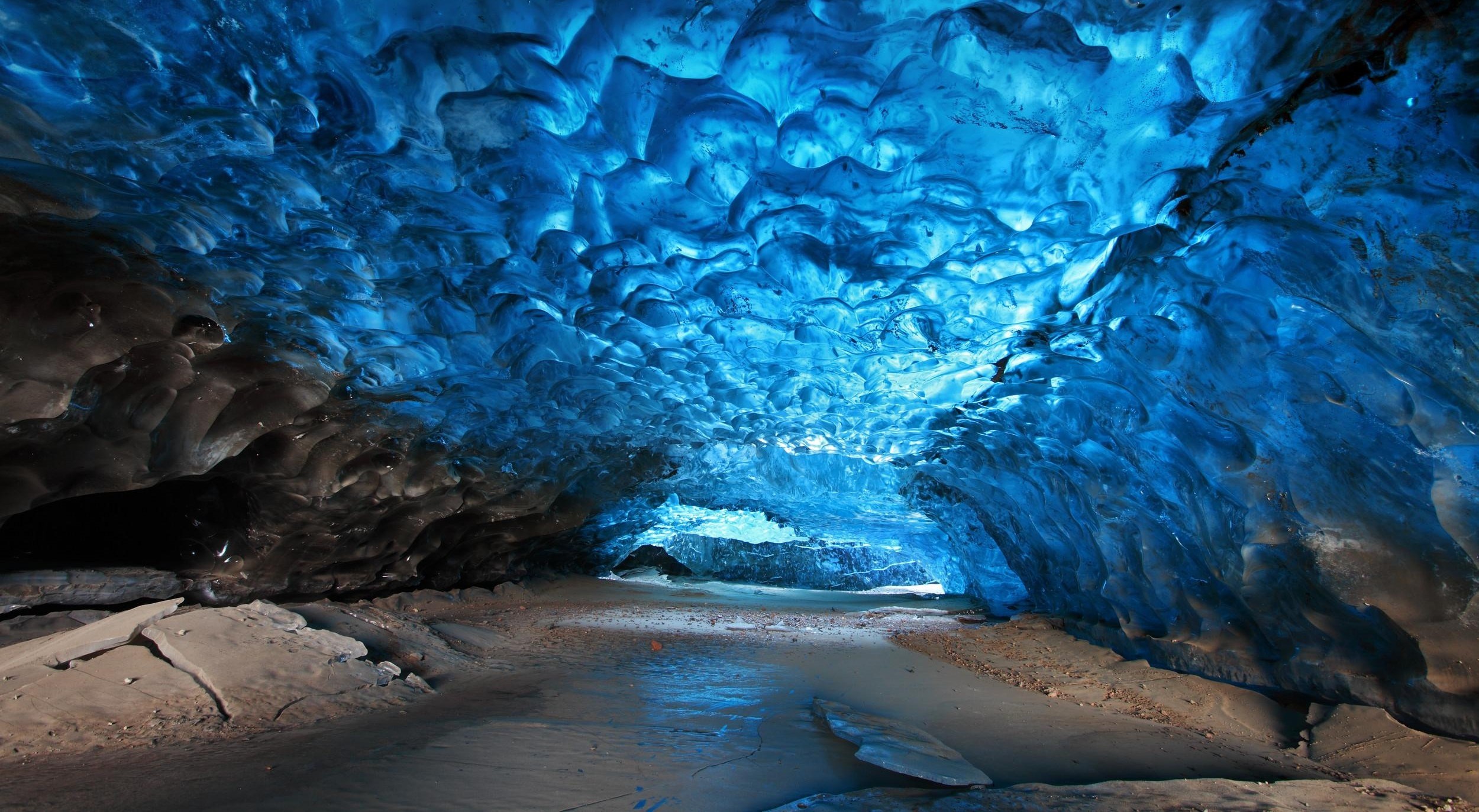 Blue ice cave with frozen stream HD Wallpaper
