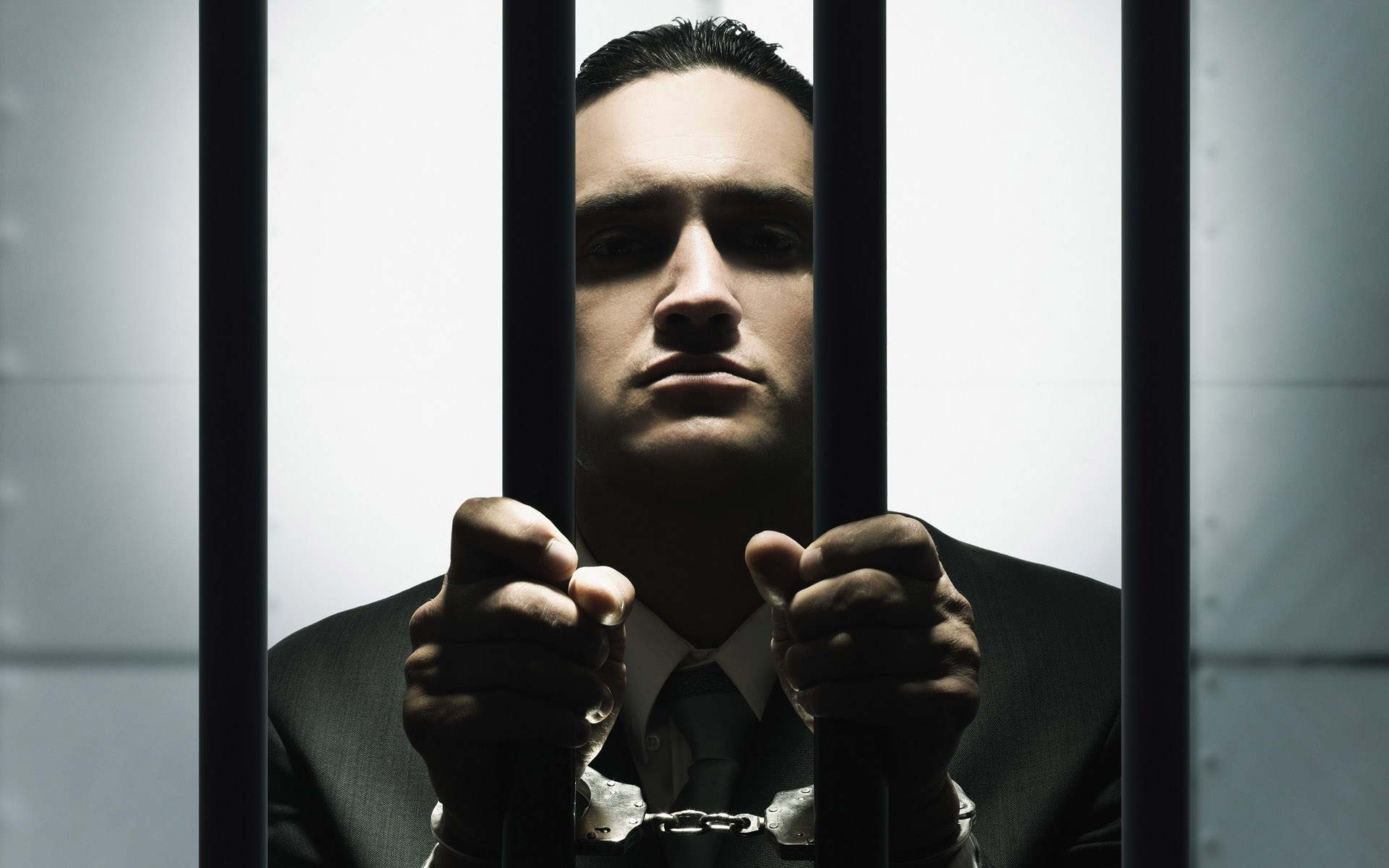 Man in handcuffs behind prison bars HD Wallpaper