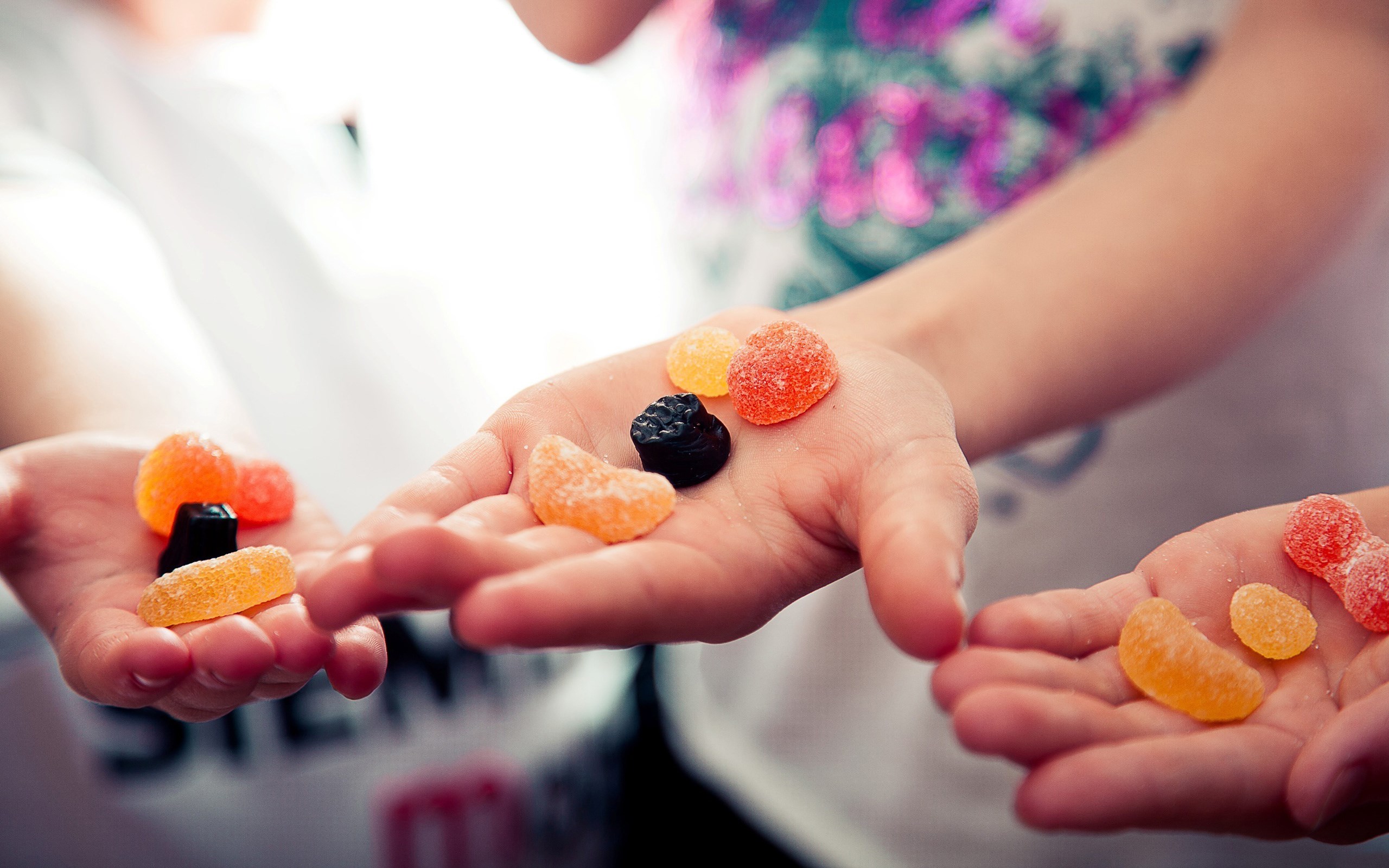 Hands holding colorful gummy candies HD Wallpaper