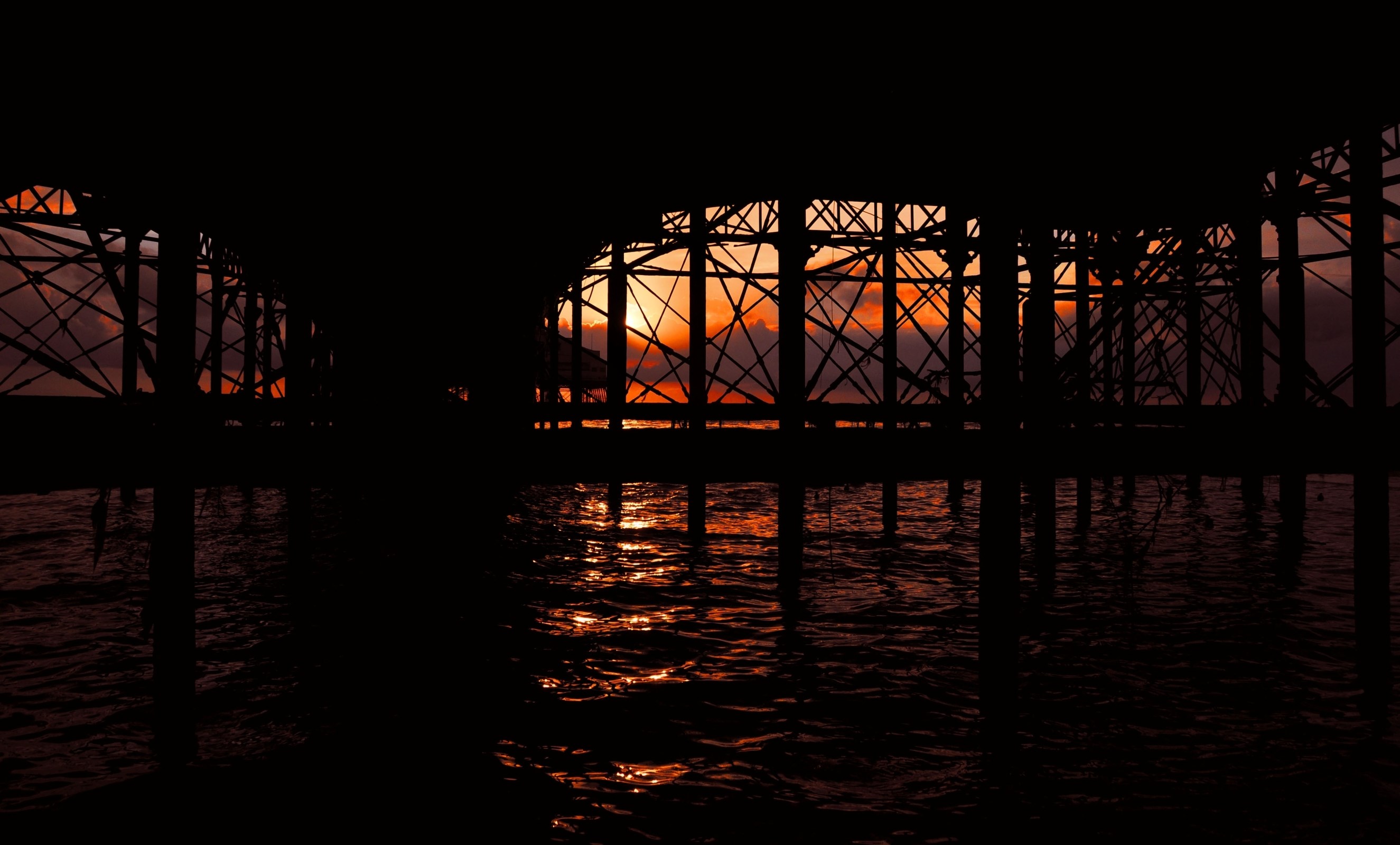 Silhouette of a pier over the ocean at sunset HD Wallpaper