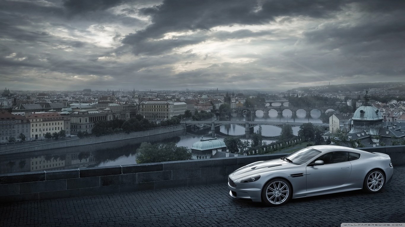 Aston Martin DBS on a cobblestone street overlooking Prague HD Wallpaper