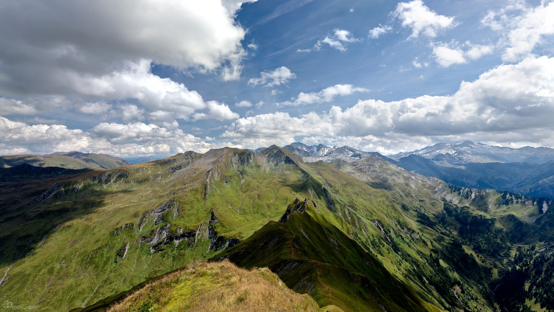 Mountain range with green slopes and cloudy sky HD Wallpaper