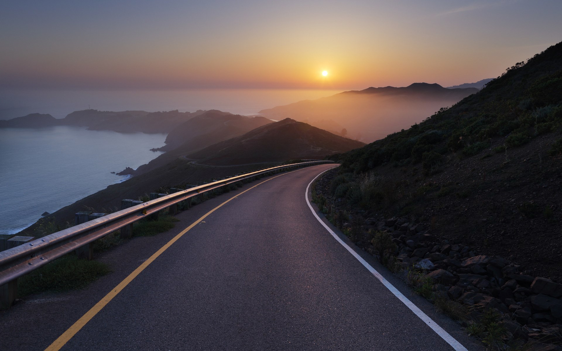 Coastal road at sunset with ocean and mountains HD Wallpaper